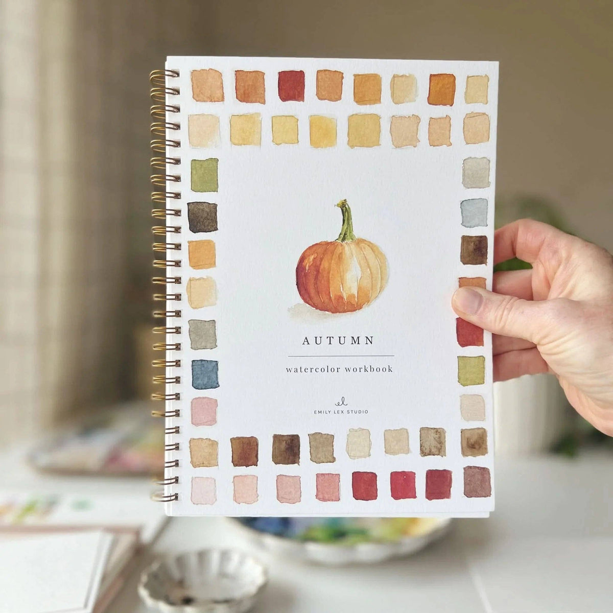 Hand holding the autumn watercolor workbook