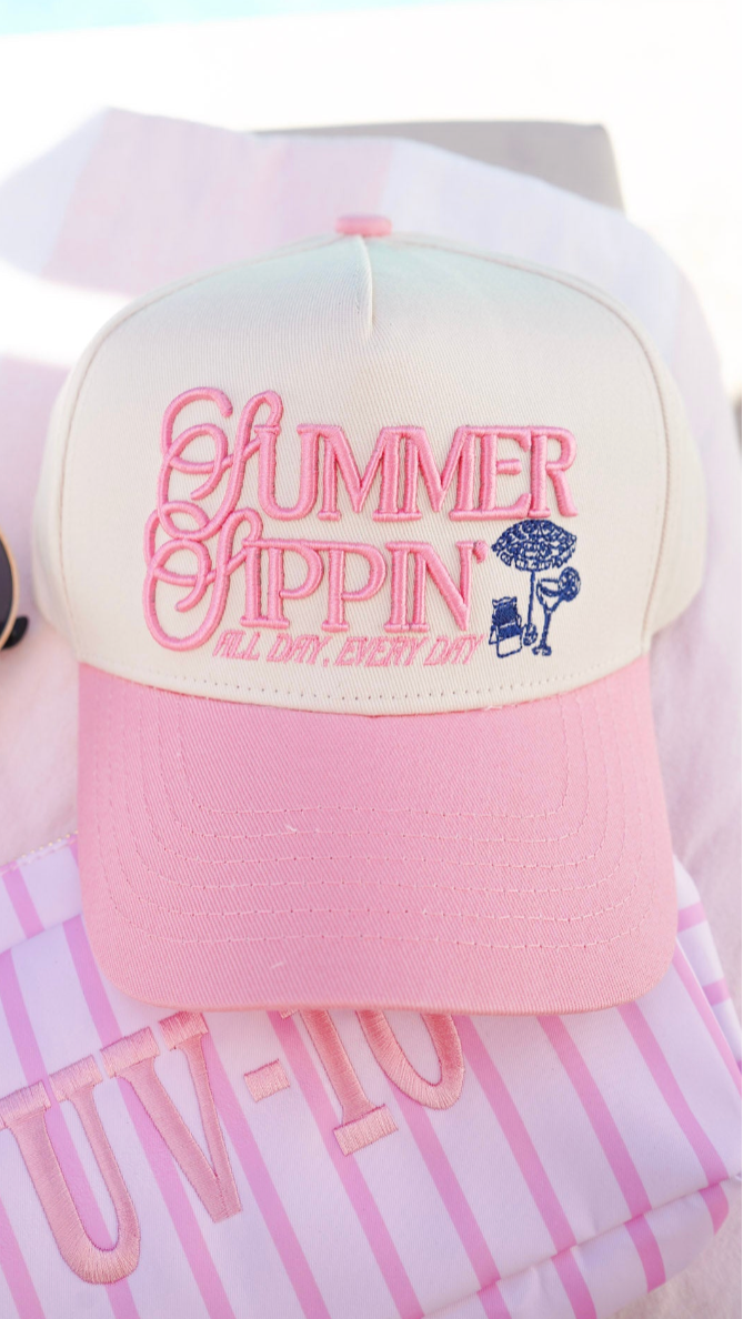 Pink and white cap with 'Summer Chillin' text, sunglasses, and striped fabric on a light blue background