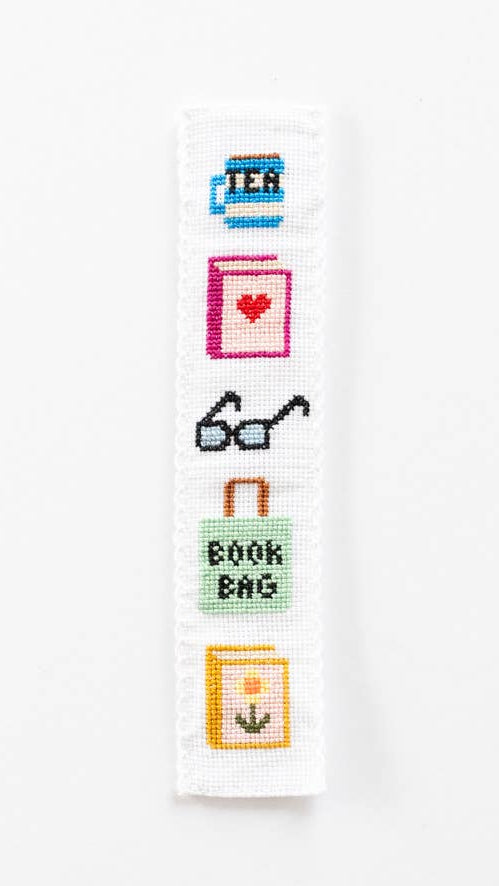 Cross-stitched bookmark with various book-themed designs on a white background