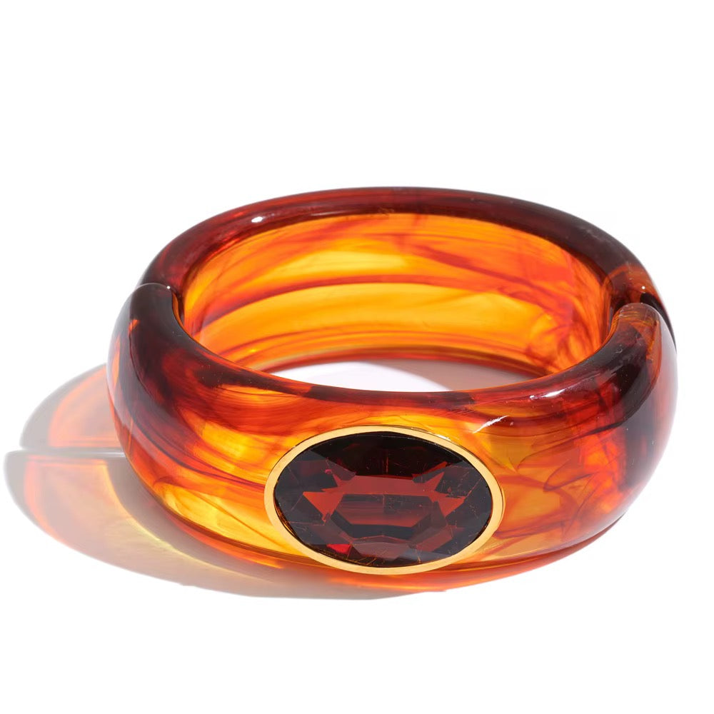 Translucent amber resin cuff bracelet with faceted garnet red oval stone in gold-tone setting