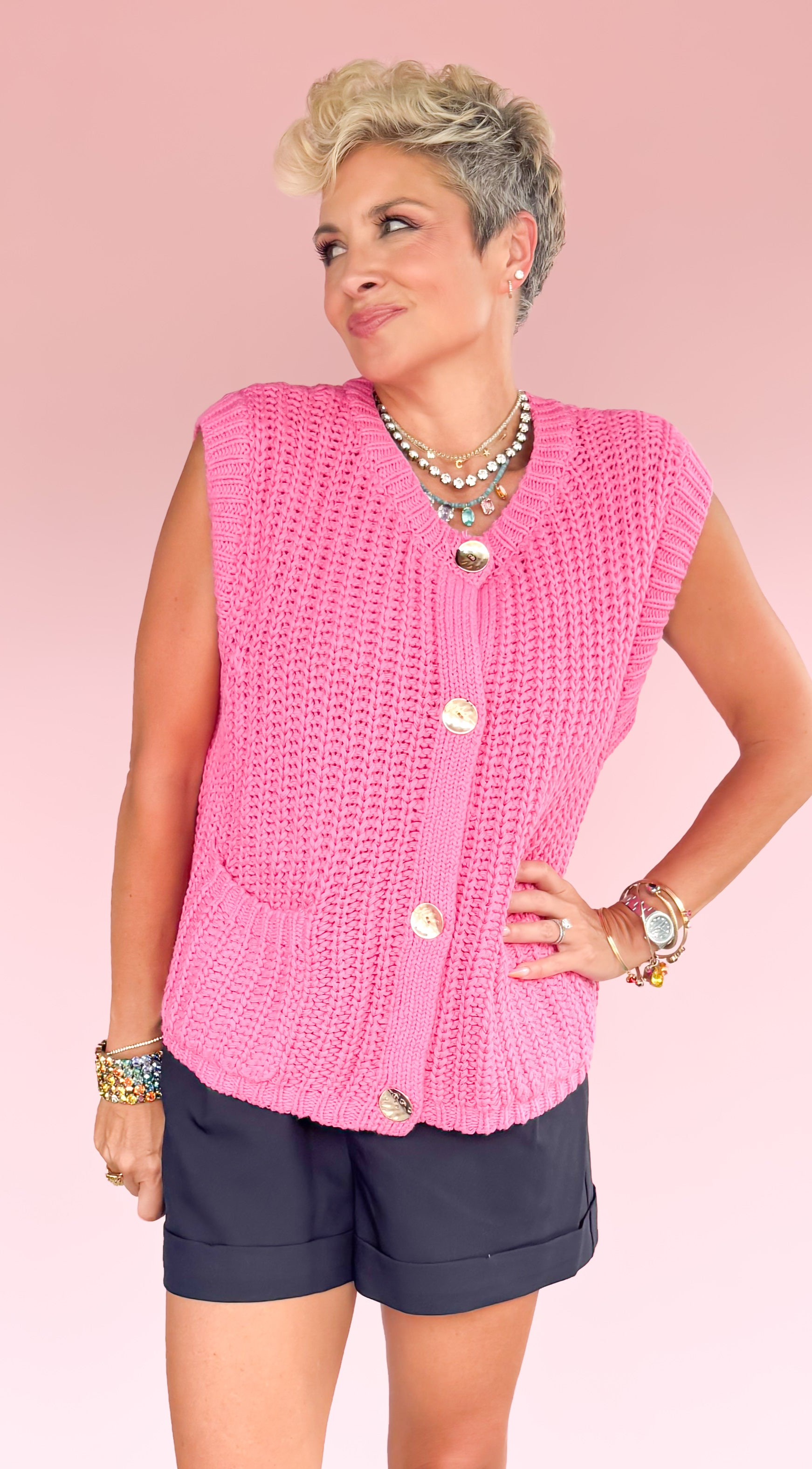 Woman wearing a pink sleeveless top and navy shorts on a pink and black geometric patterned floor.