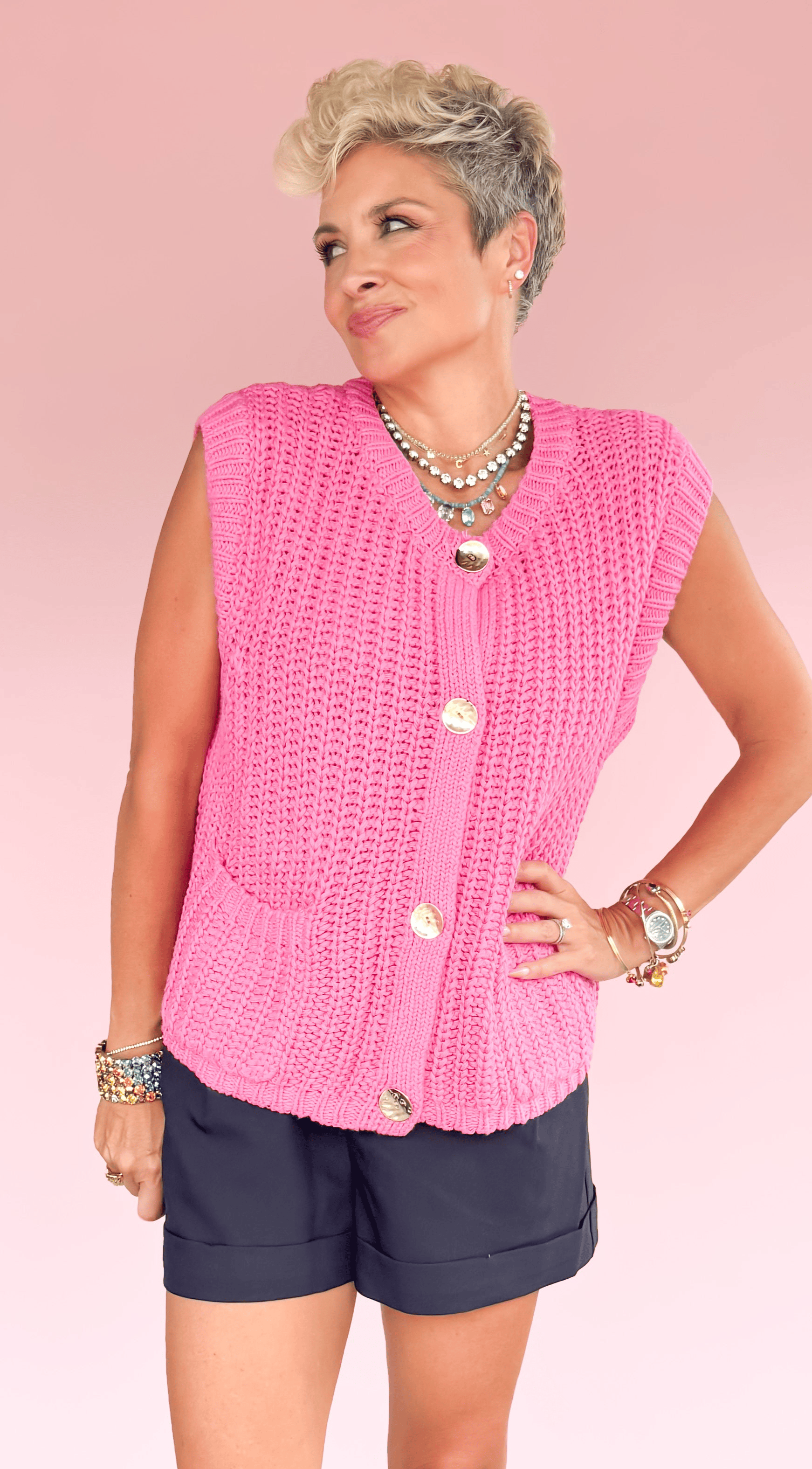 Woman wearing a pink sleeveless top and navy shorts on a pink and black geometric patterned floor.