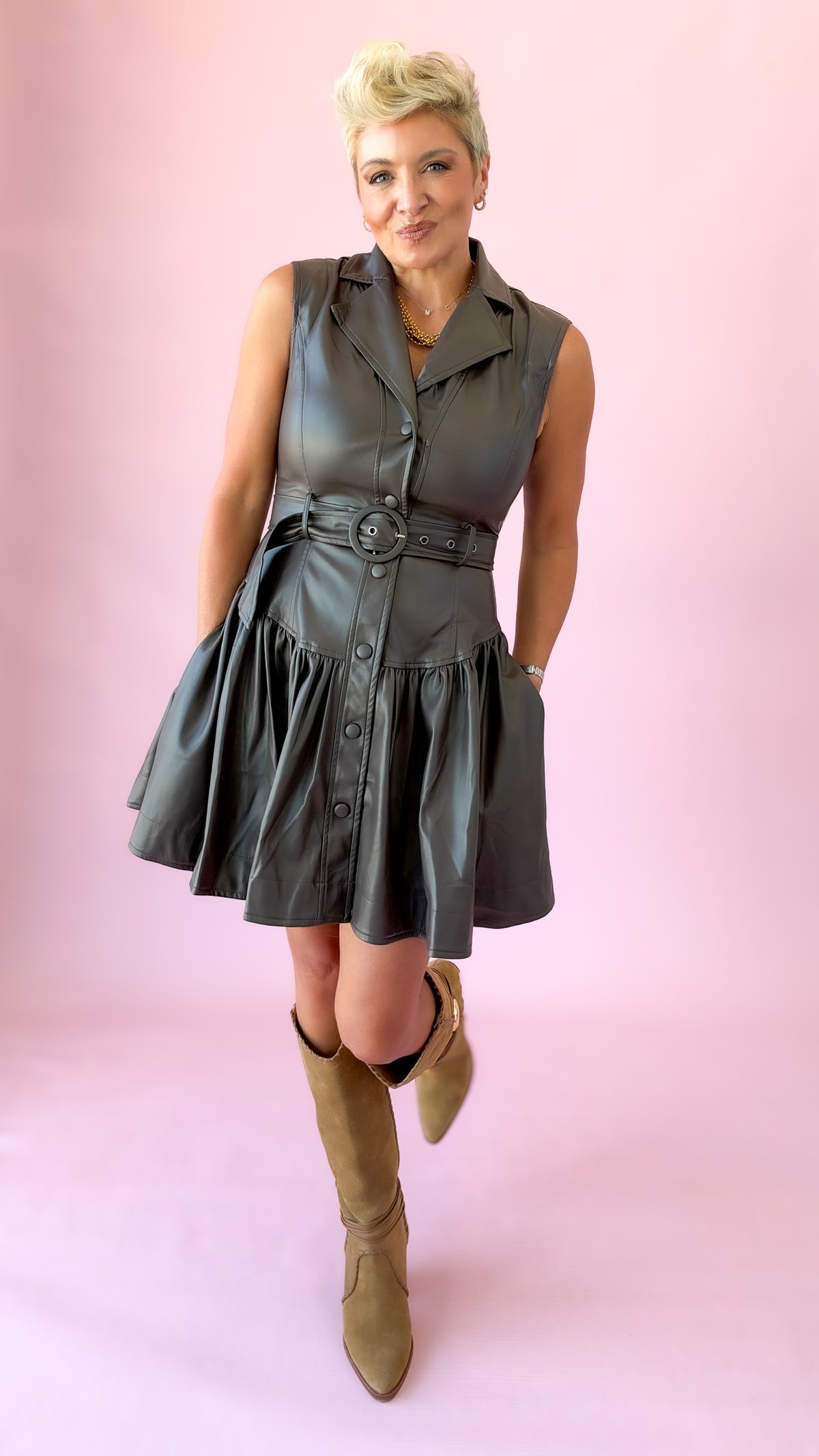 Brown faux leather sleeveless belted mini dress with collar and flared skirt, worn with tan boots