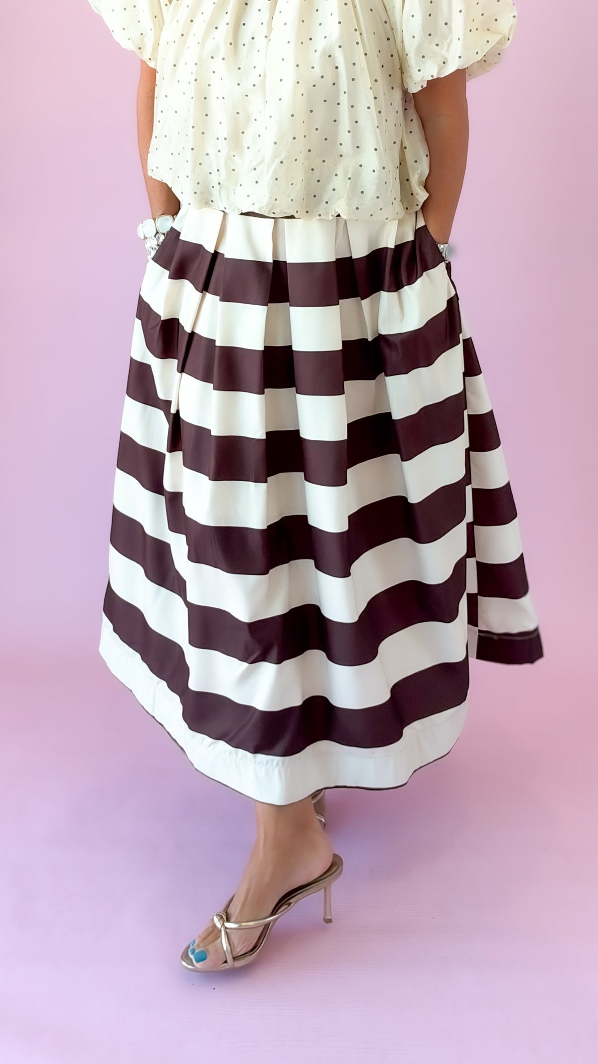 Close-up of brown and white wide stripe pleated midi skirt with an ivory top
