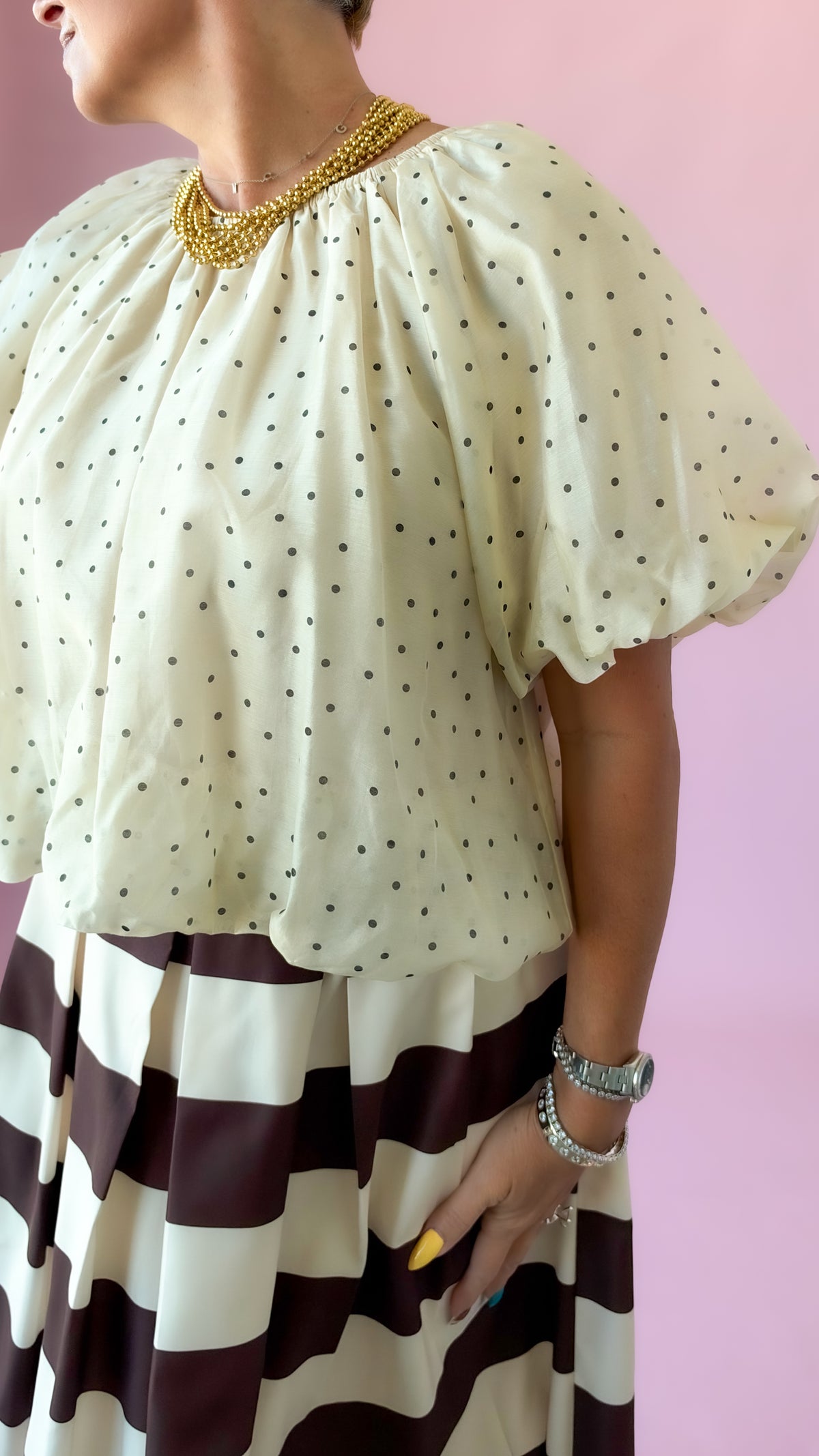 Close-up of the dotted fabric and puff sleeves on the ivory flutter top