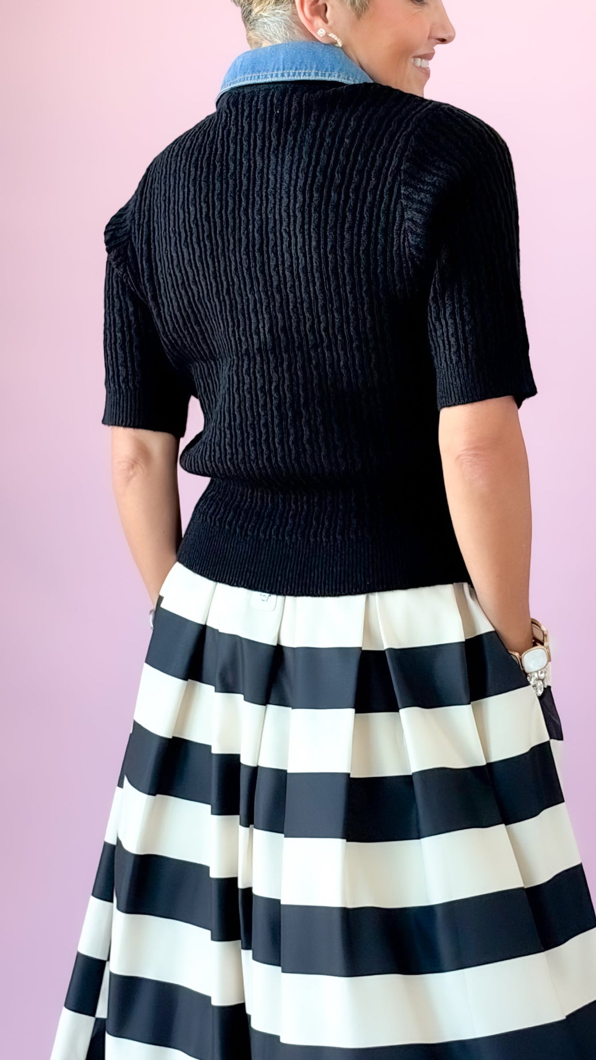Back view of black cable knit sweater with denim collar