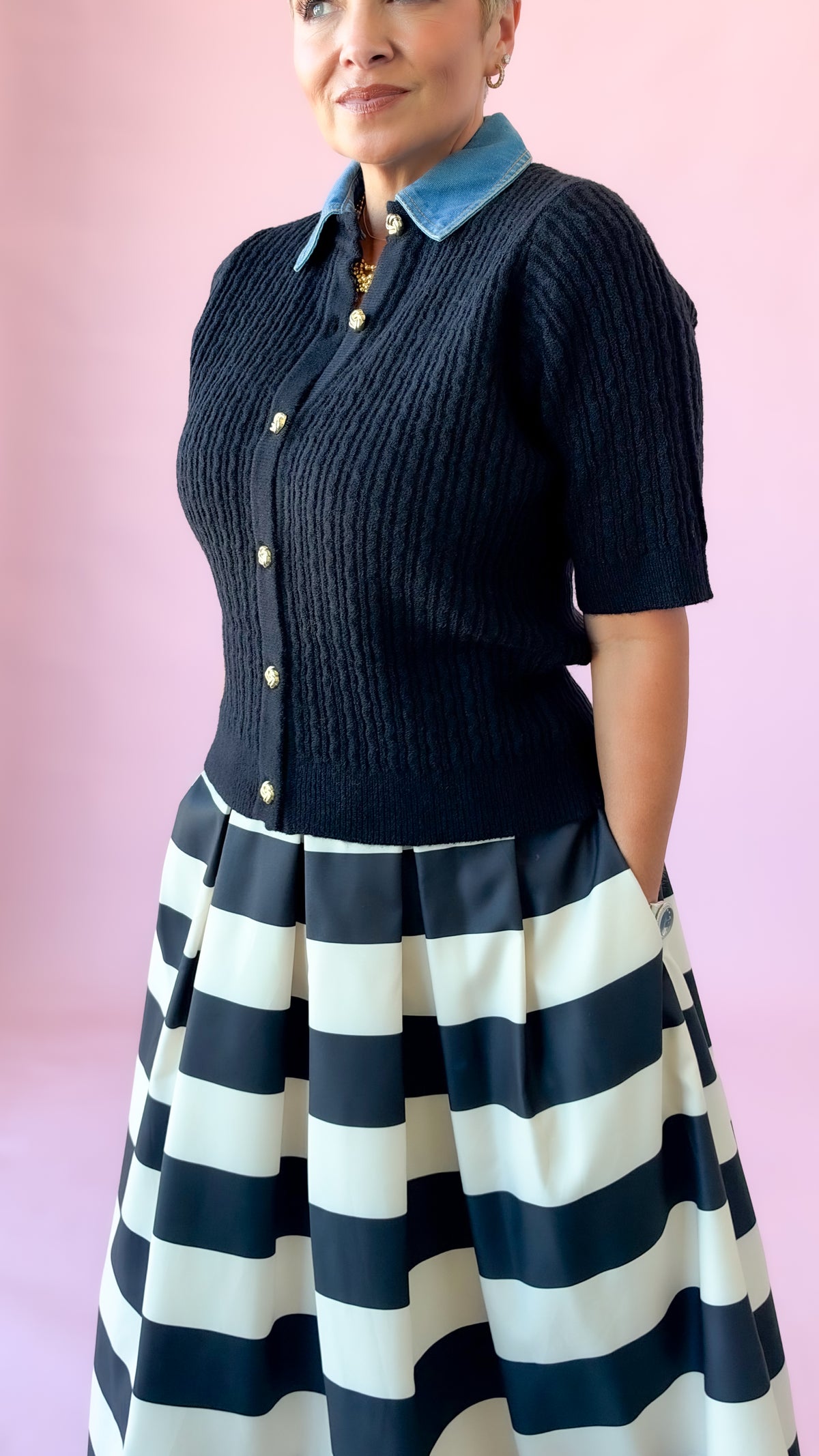 Black cable knit denim collar sweater tucked into a black and white striped skirt