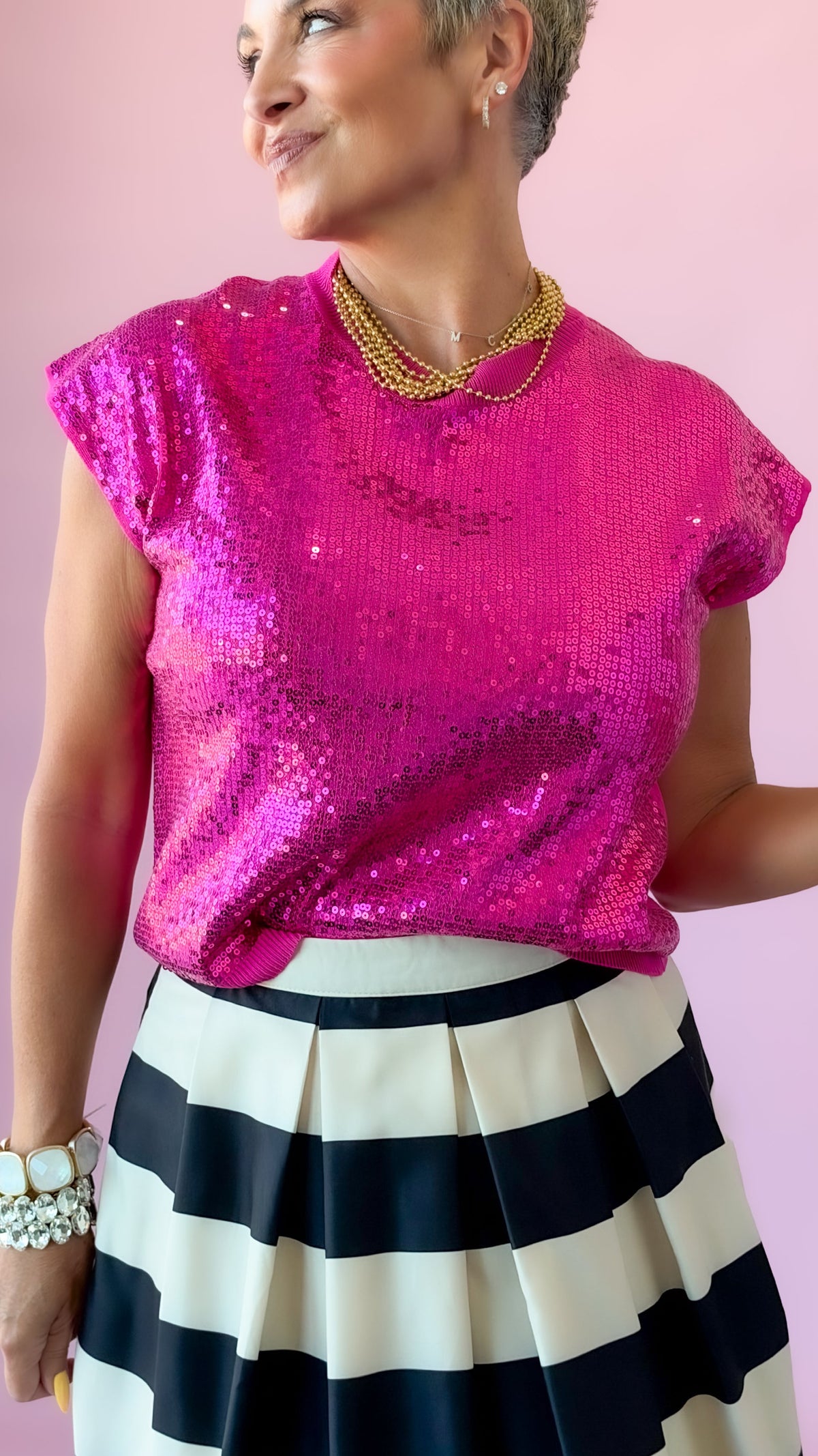 Close-up of hot pink Sierra sequin short sleeve top with a striped skirt