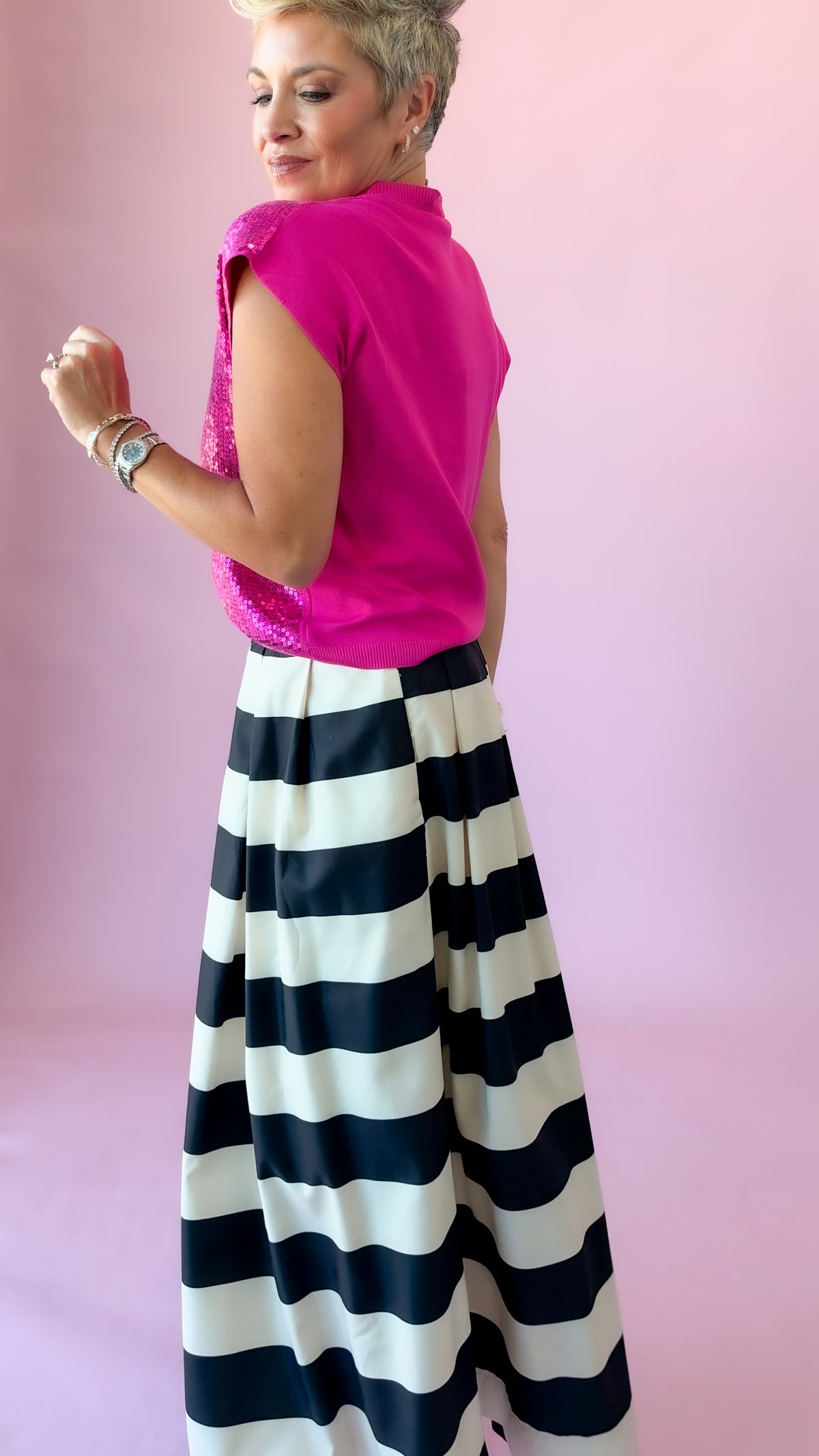Side view of hot pink Sierra sequin top with black and white striped skirt