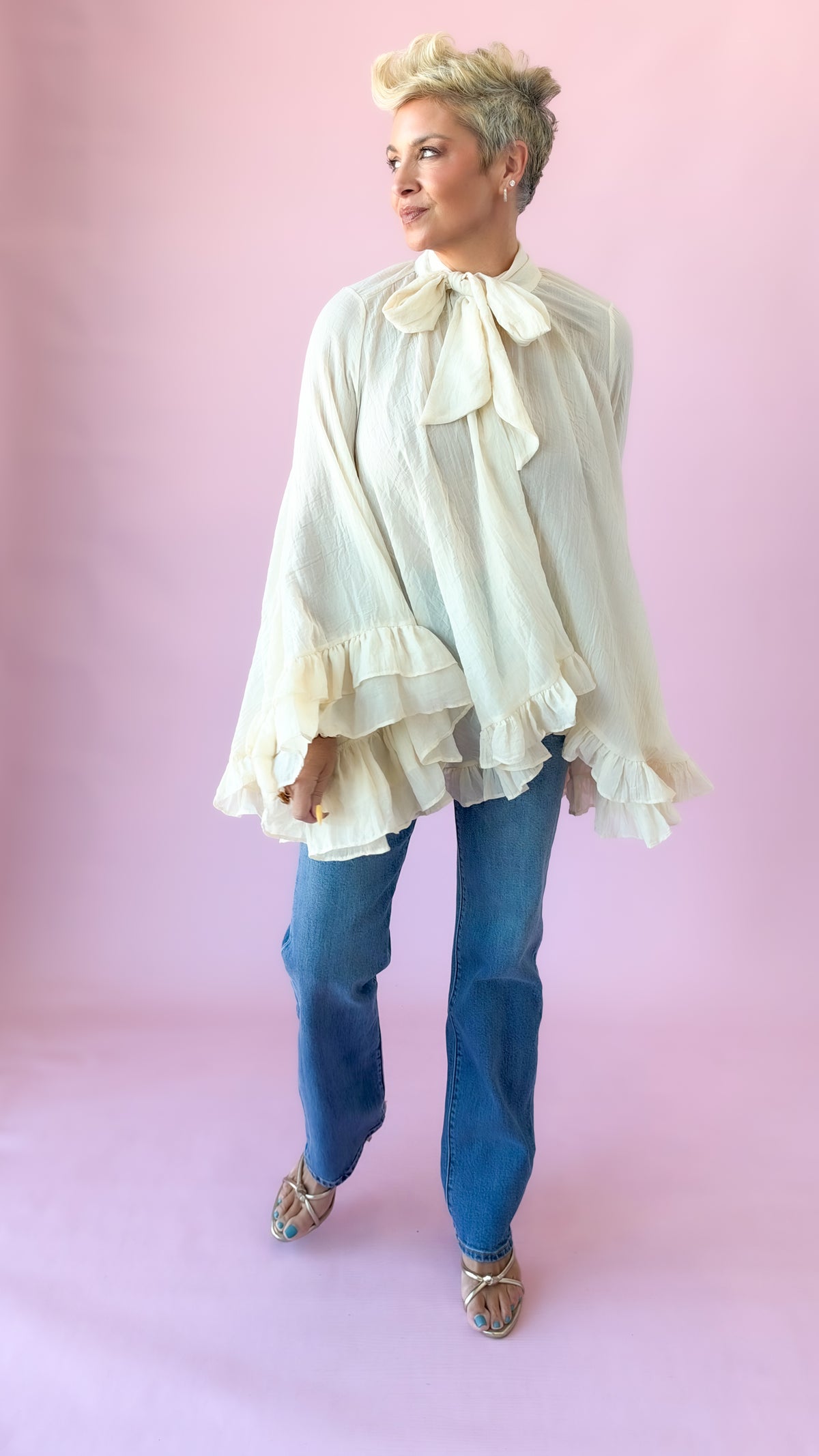 Full-length view of cream oversized blouse with bow tie neck and straight jeans