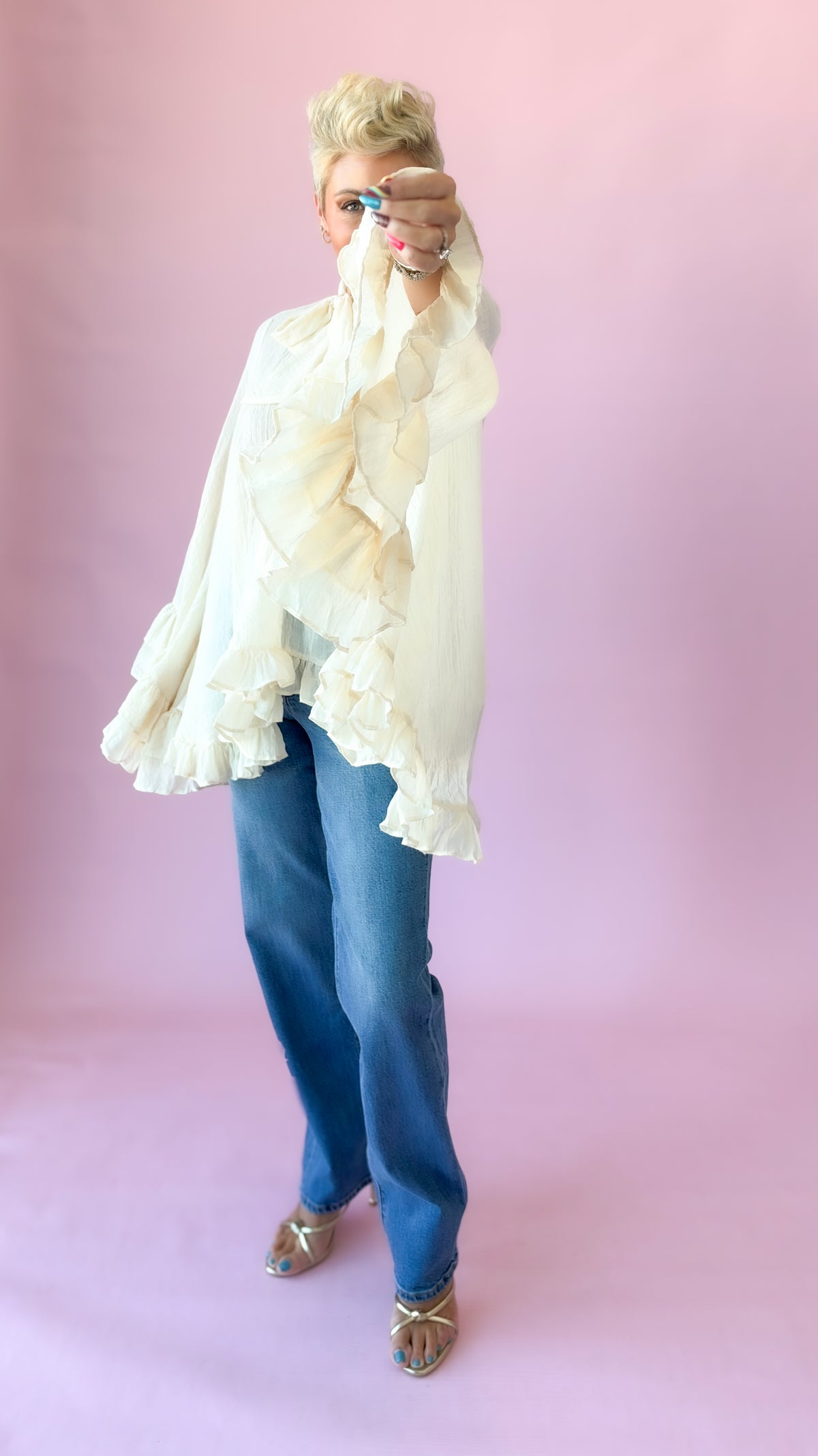 Side view of cream oversized bow blouse with ruffled sleeves and jeans