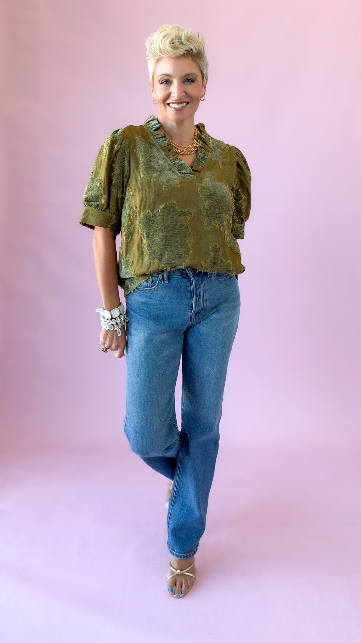Model walking in olive luxe patchwork short sleeve top and jeans