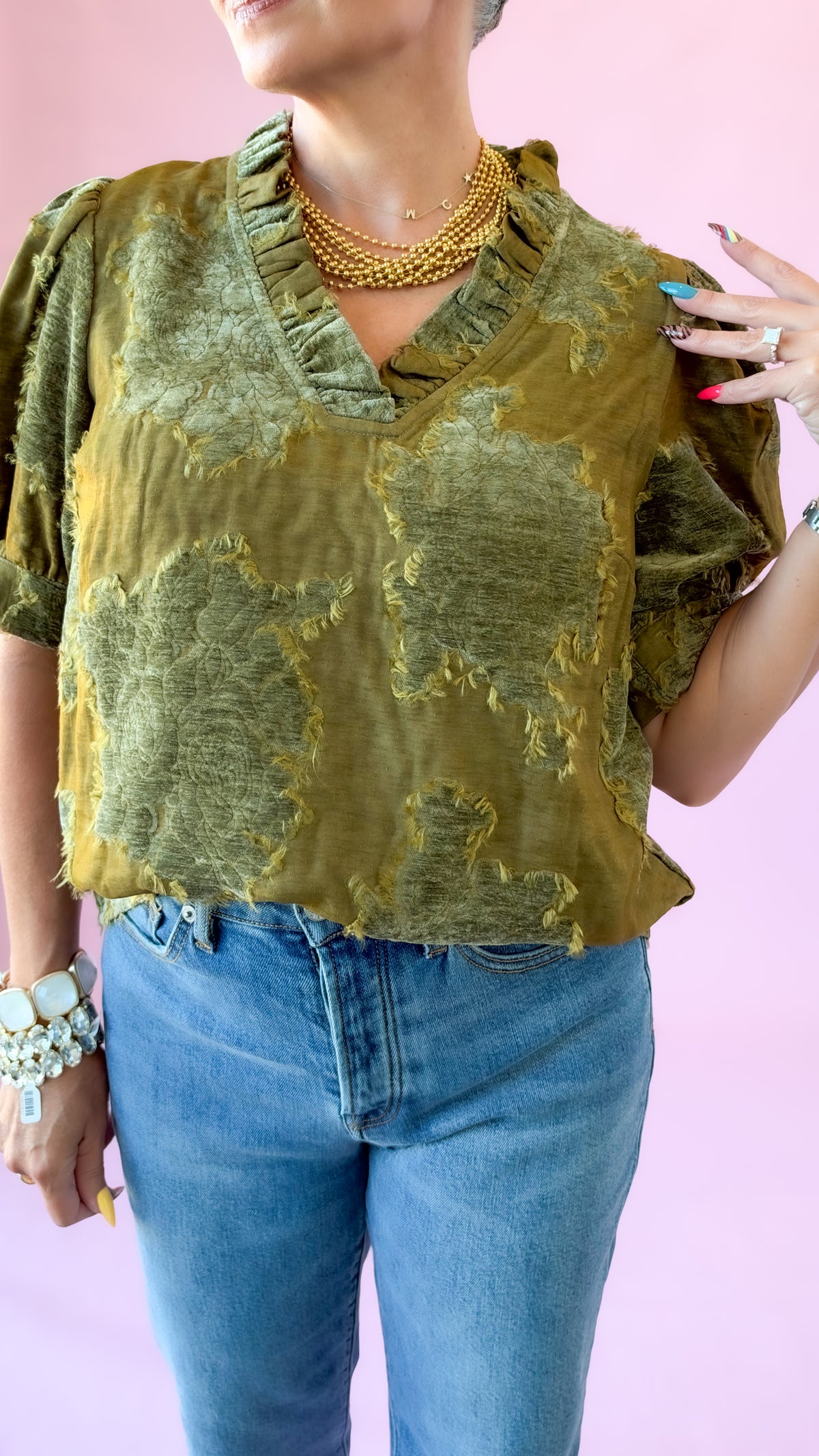 Close-up of olive textured luxe patchwork top with ruffled V-neck and puff short sleeves