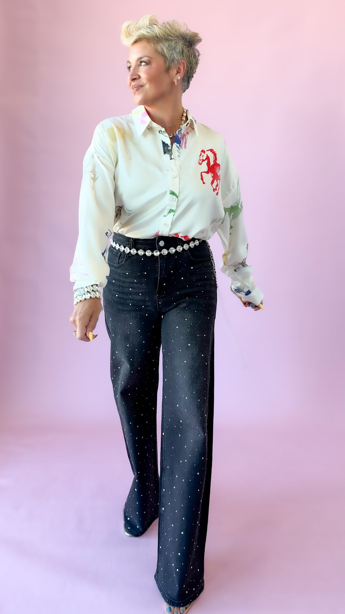 Full-length view of black studded jeans with pearl belt and white embroidered blouse