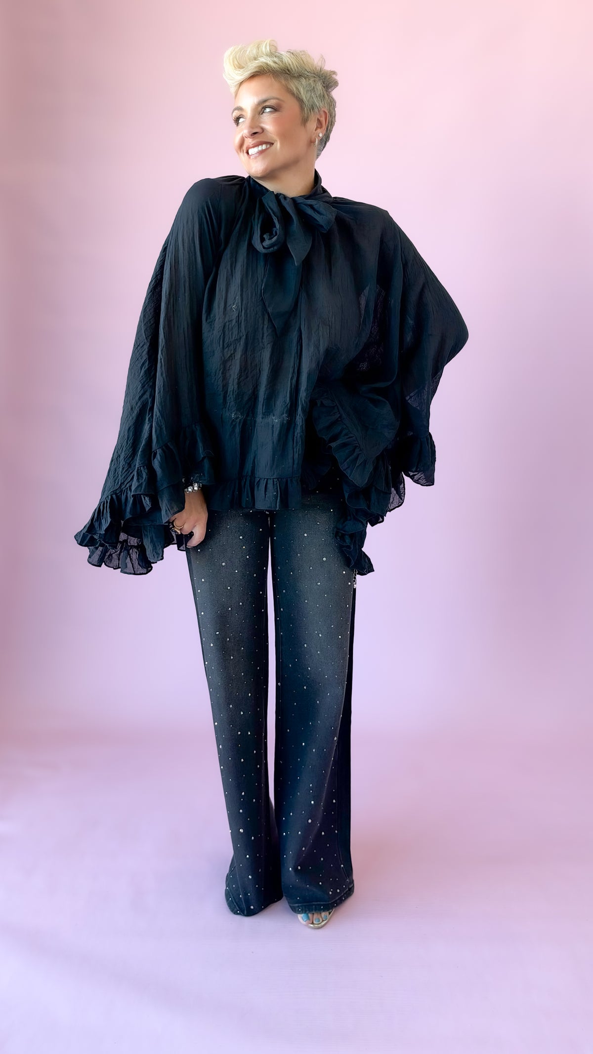 Full-length view of black oversized bow blouse with studded dark jeans