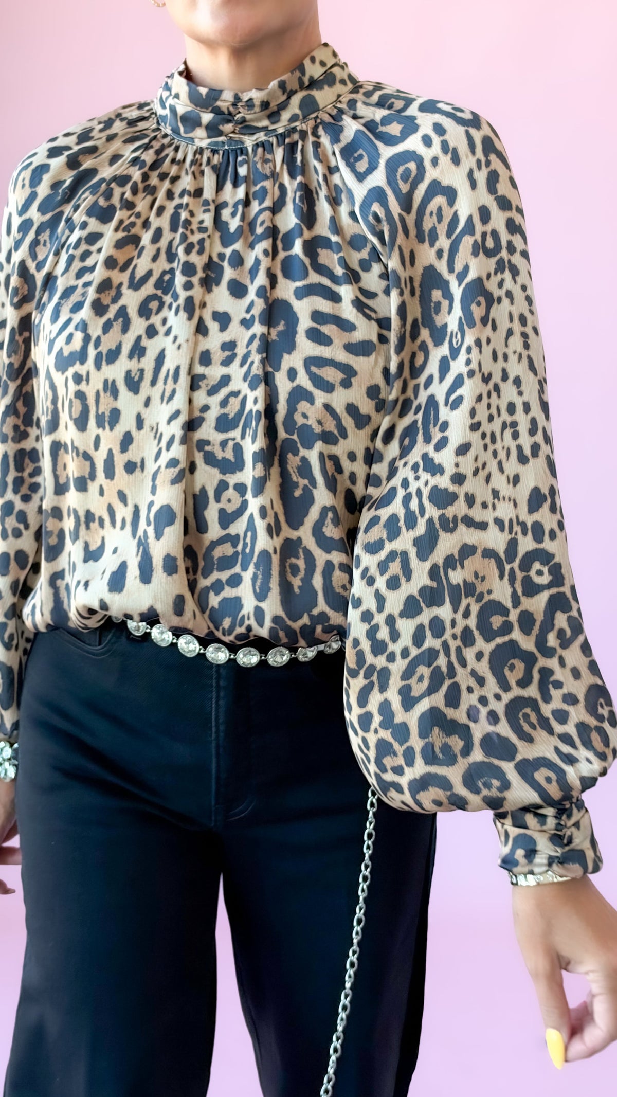 Close-up of Jessie leopard print long sleeve blouse with mock neck, worn with black pants