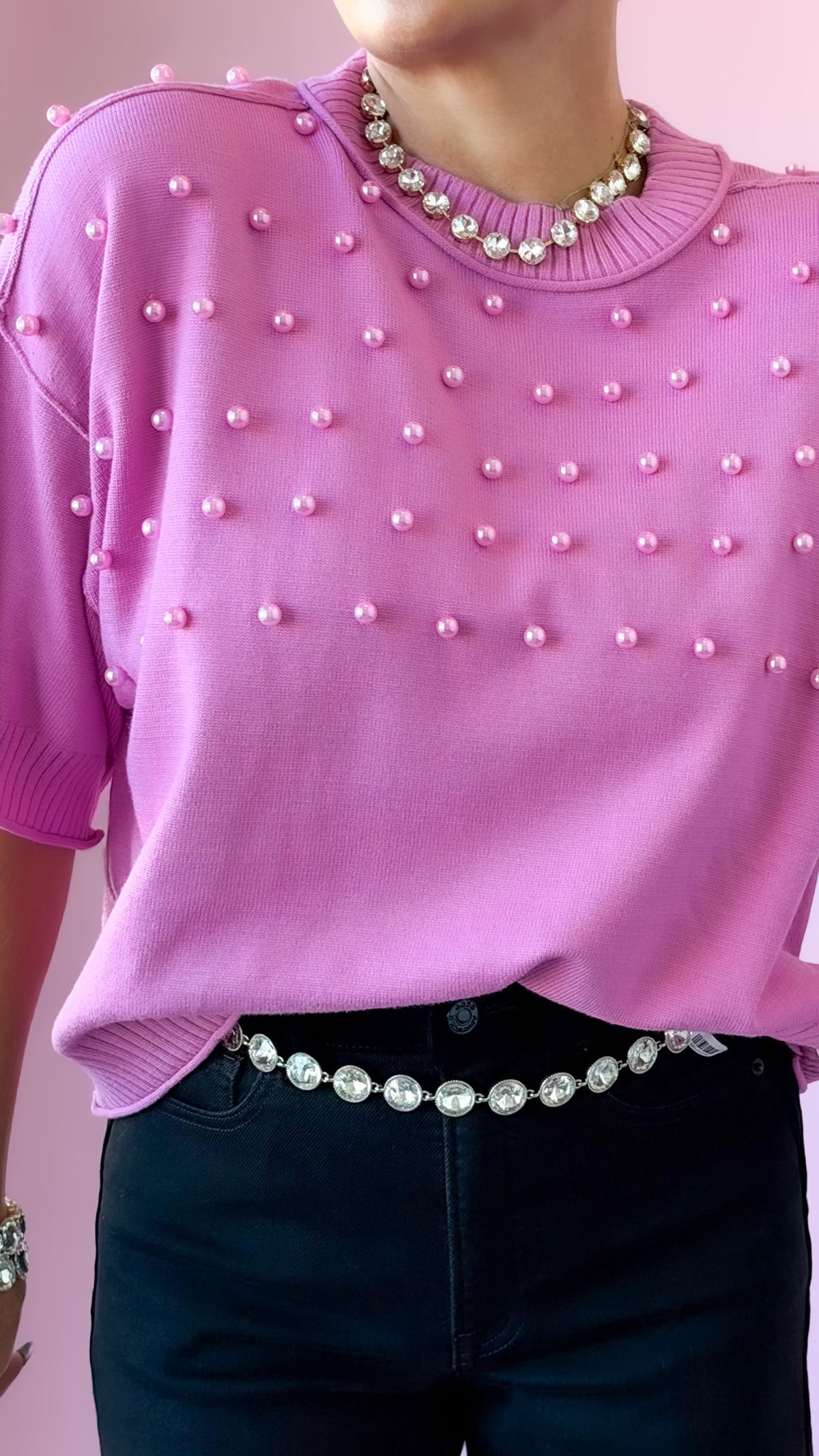 Close-up of the pearl detailing on the pink crewneck sweater