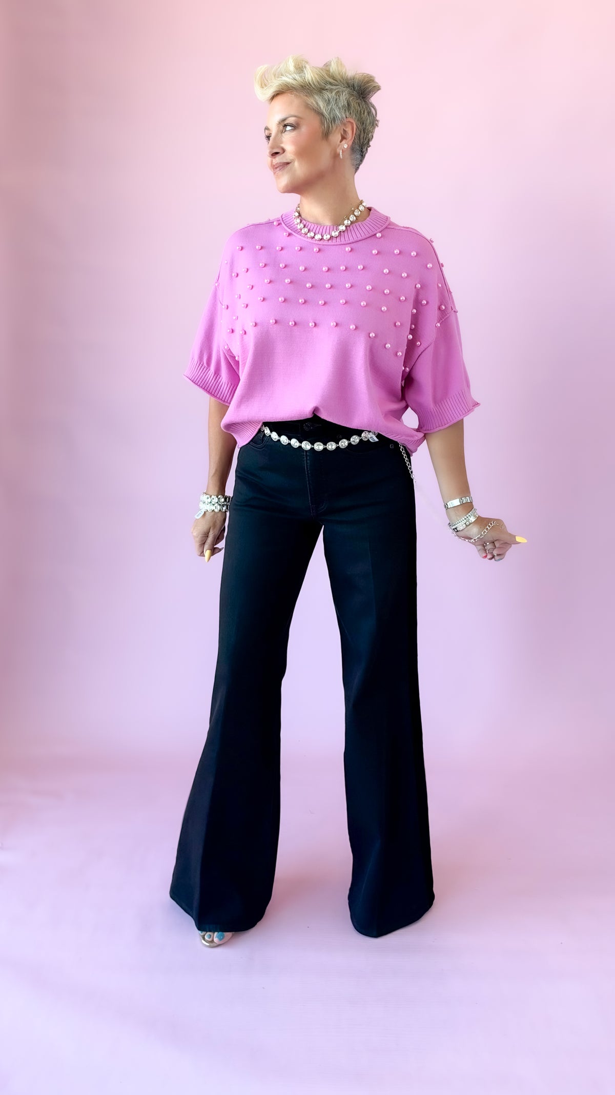 Full-length view of pink pearl crewneck sweater with black flares