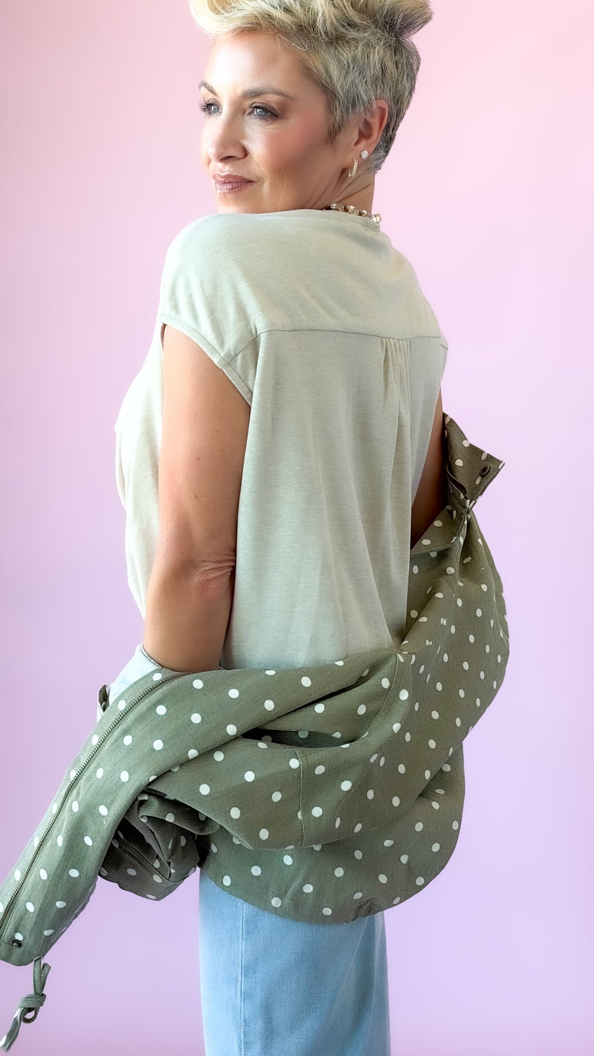 Back view of beige cap sleeve top with jacket slipped off the shoulders