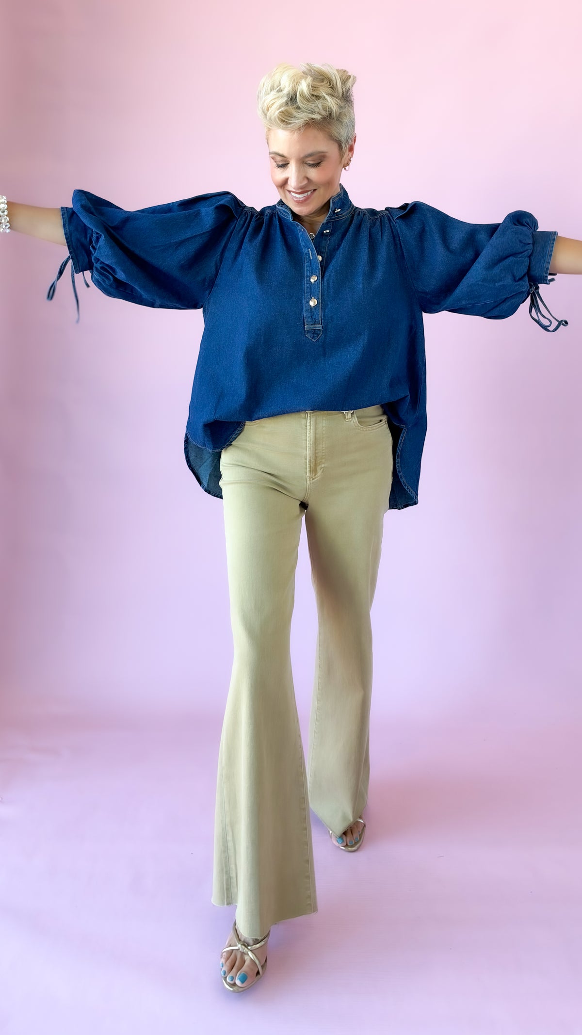 Khaki Fiona flare jeans styled with a dark denim puff sleeve top, arms outstretched
