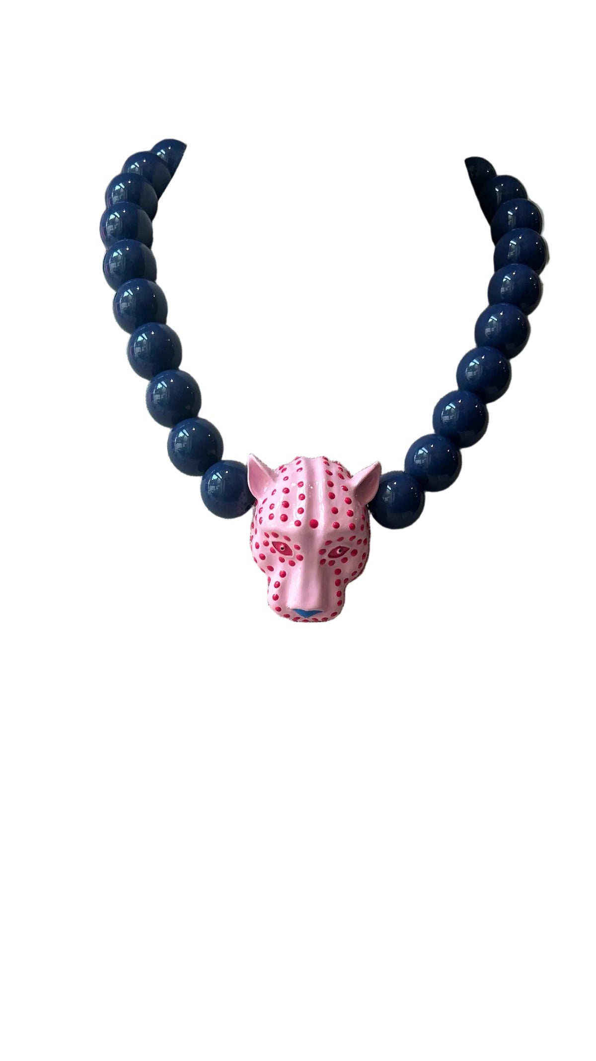 A beaded necklace displayed on a beige fabric jewelry bust. The necklace features dark blue round beads and a pink fox head pendant with white spots.