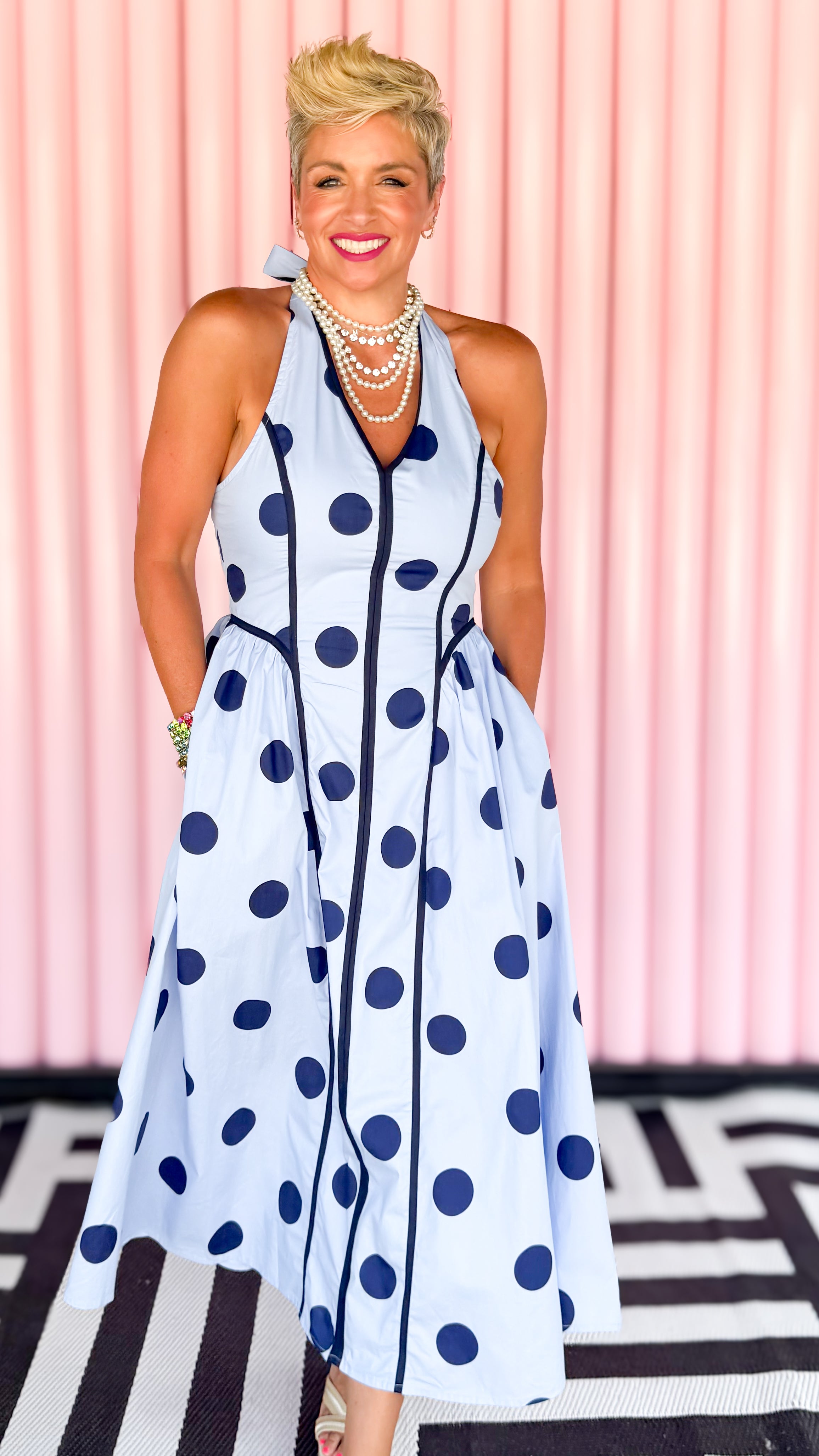 Woman wearing a polka dot dress with a pink background