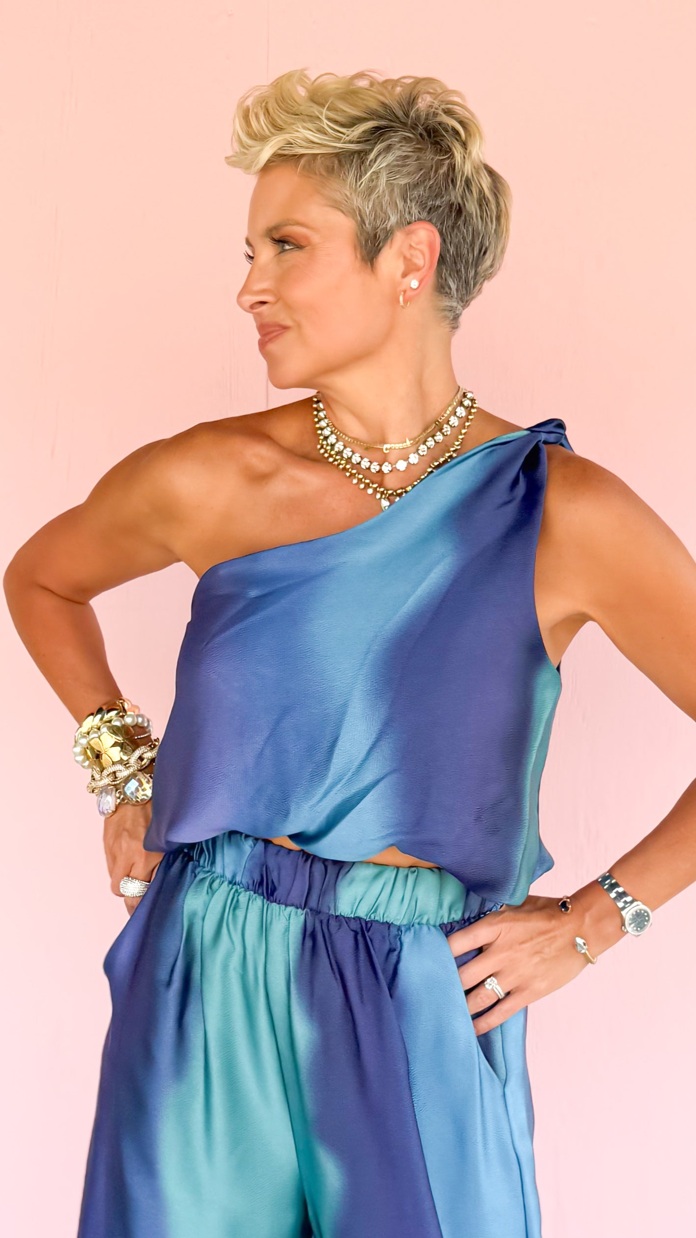Woman wearing a blue satin outfit on a pink and black geometric patterned floor.