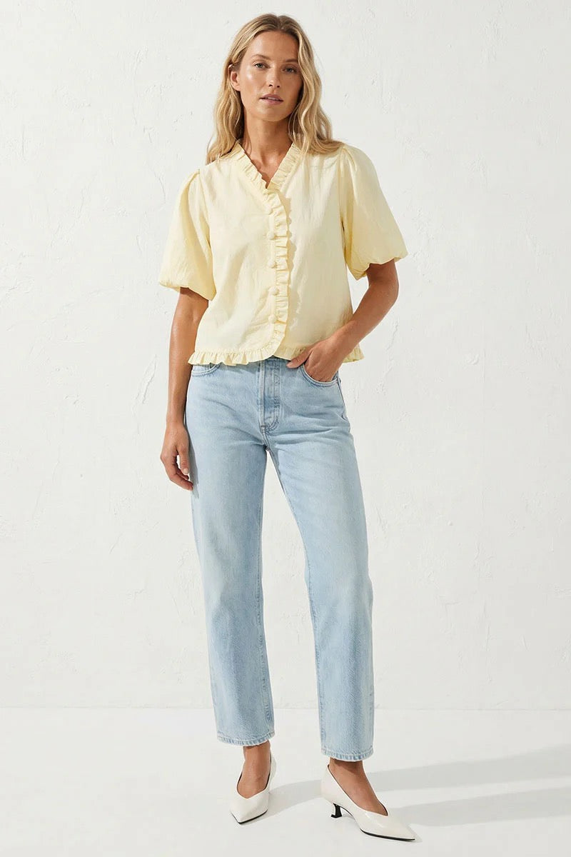 Woman wearing a light yellow blouse and light blue jeans on a white background