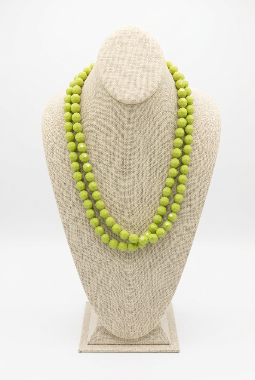 48-inch light green faceted bead necklace worn doubled in two layered strands on a beige linen jewelry bust