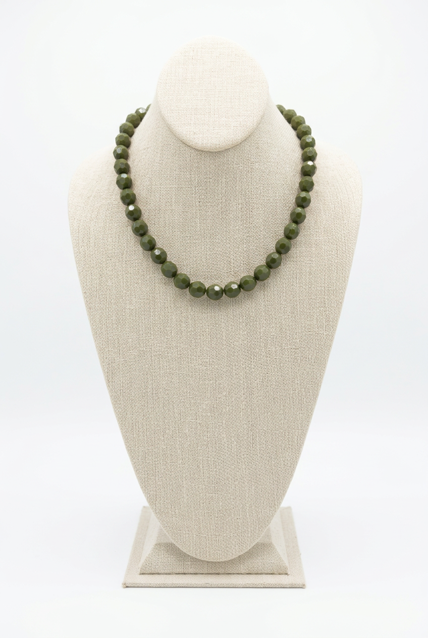 18-inch olive green faceted bead necklace displayed on a beige linen jewelry bust