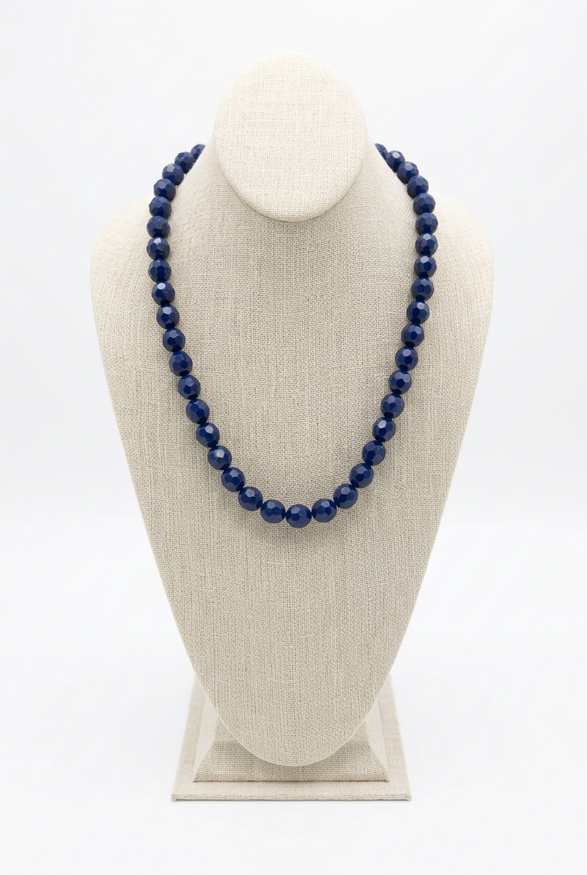 18-inch navy blue faceted bead necklace displayed on a beige linen jewelry bust