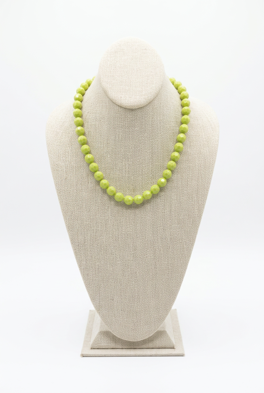 18-inch light green faceted bead necklace displayed on a beige linen jewelry bust