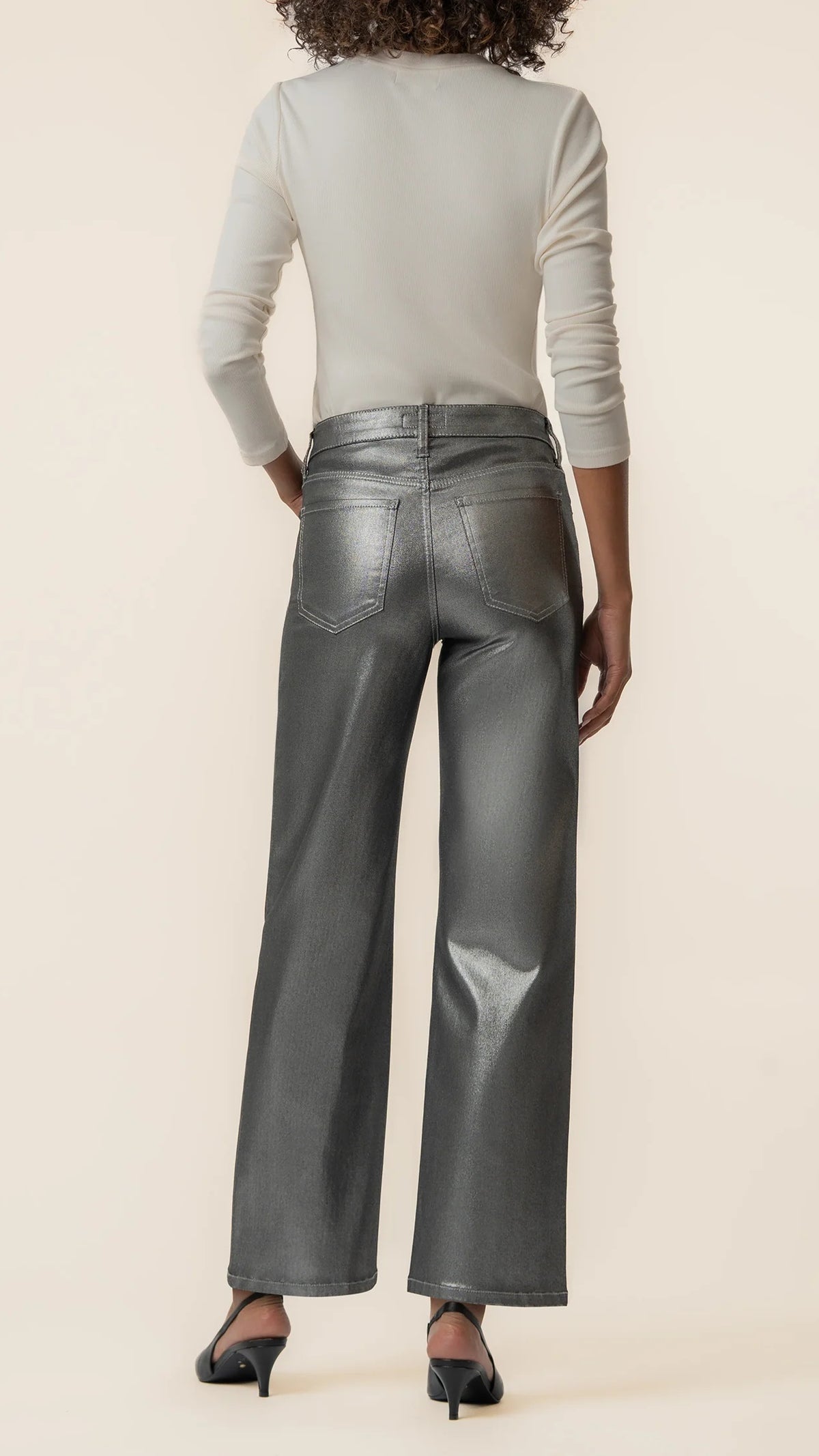 Back view of matte silver wide leg jeans with black heels