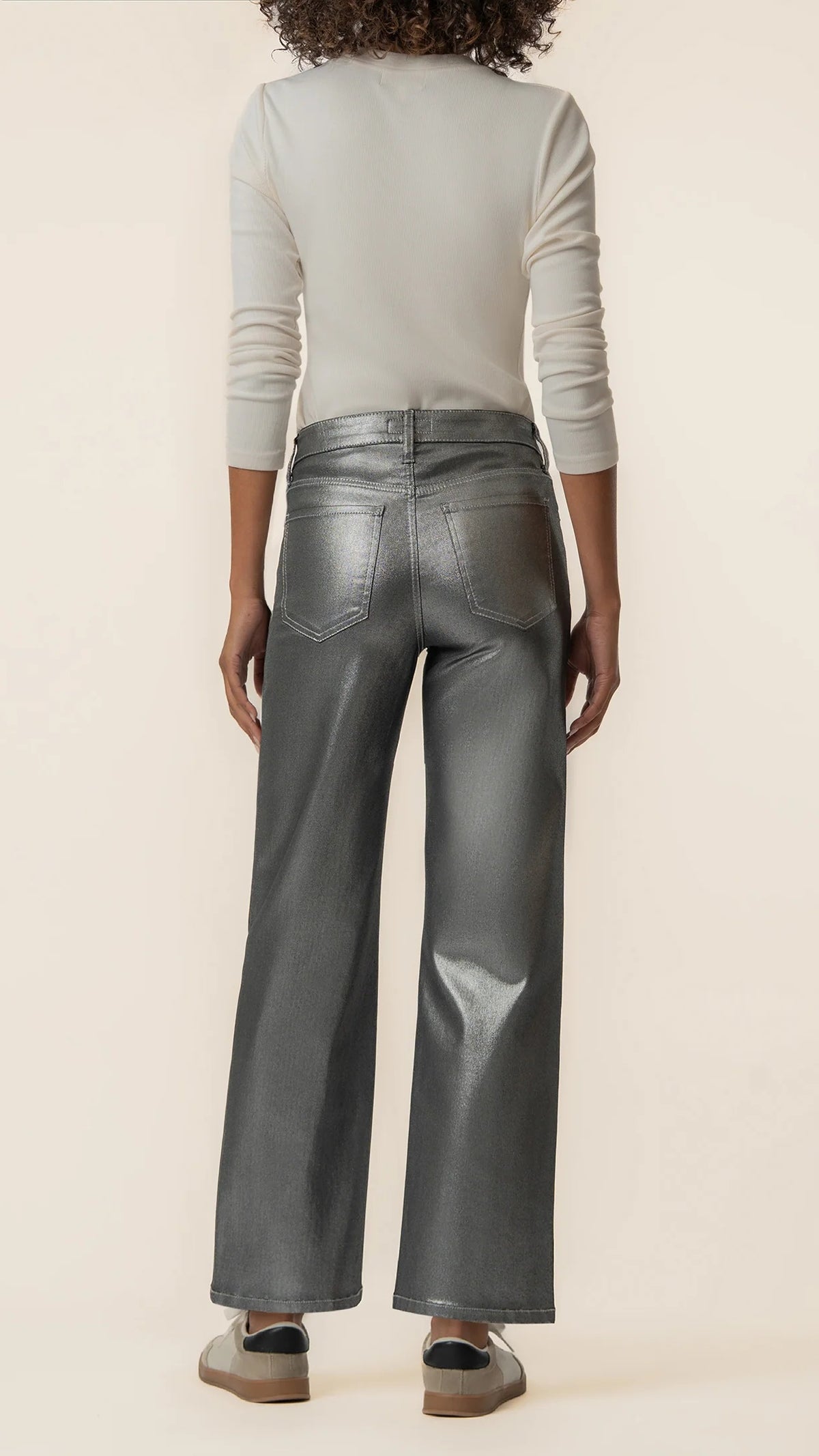 Back view of matte silver wide leg jeans styled with sneakers