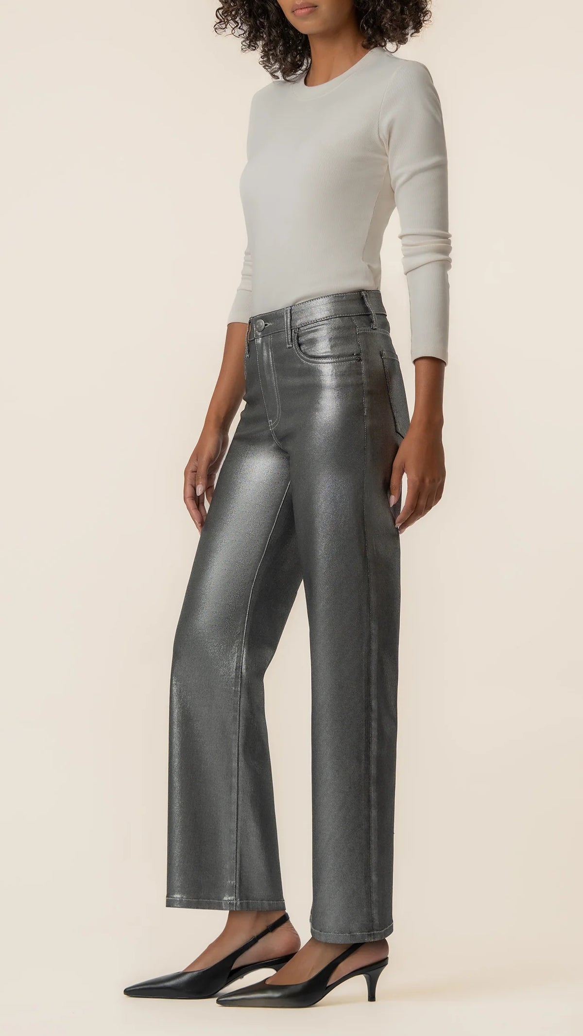 Three-quarter side view of matte silver wide leg jeans with black slingback heels