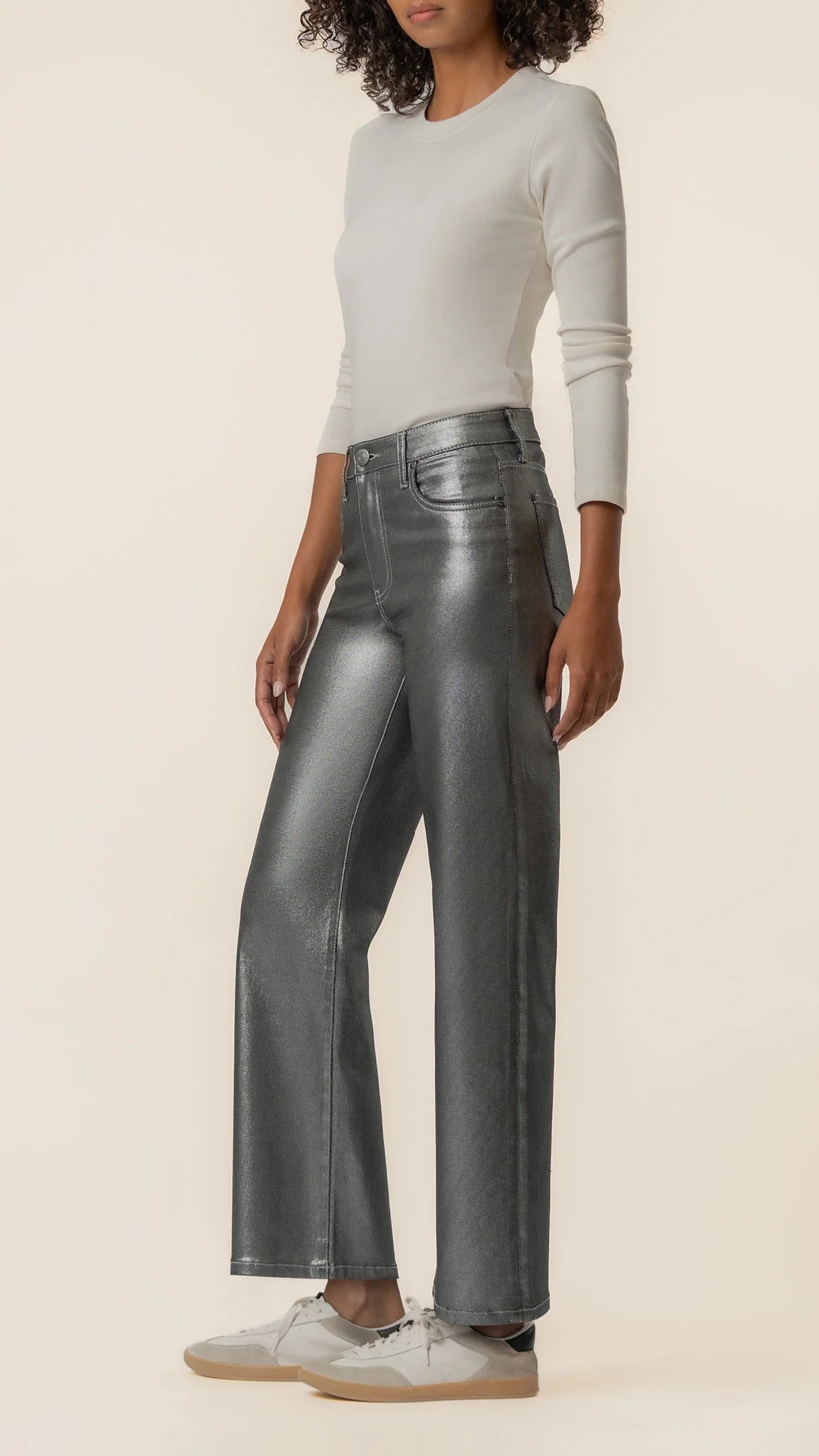 Side view of matte silver wide leg jeans styled with sneakers