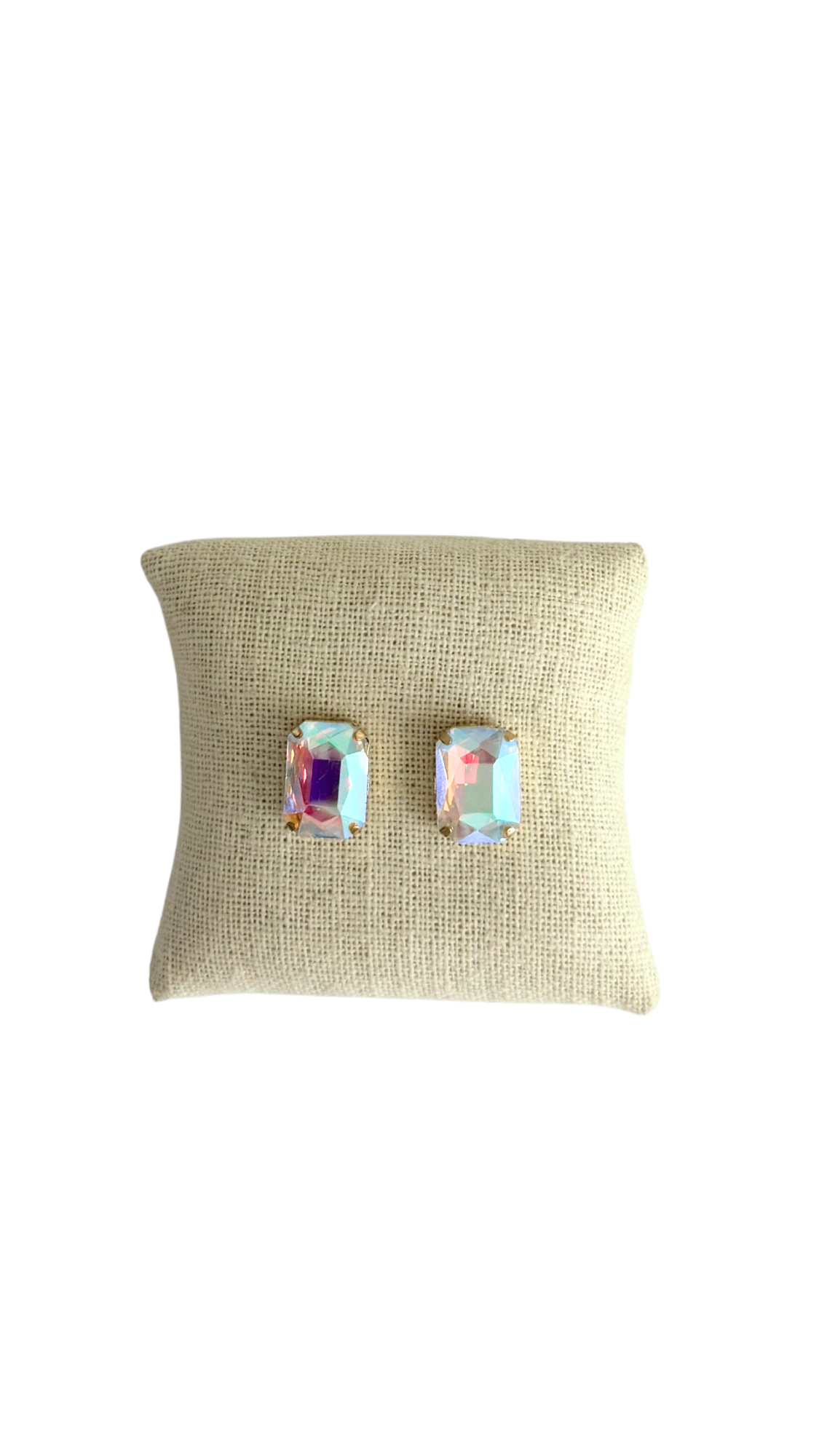 Pair of earrings on a beige cushion with a white background