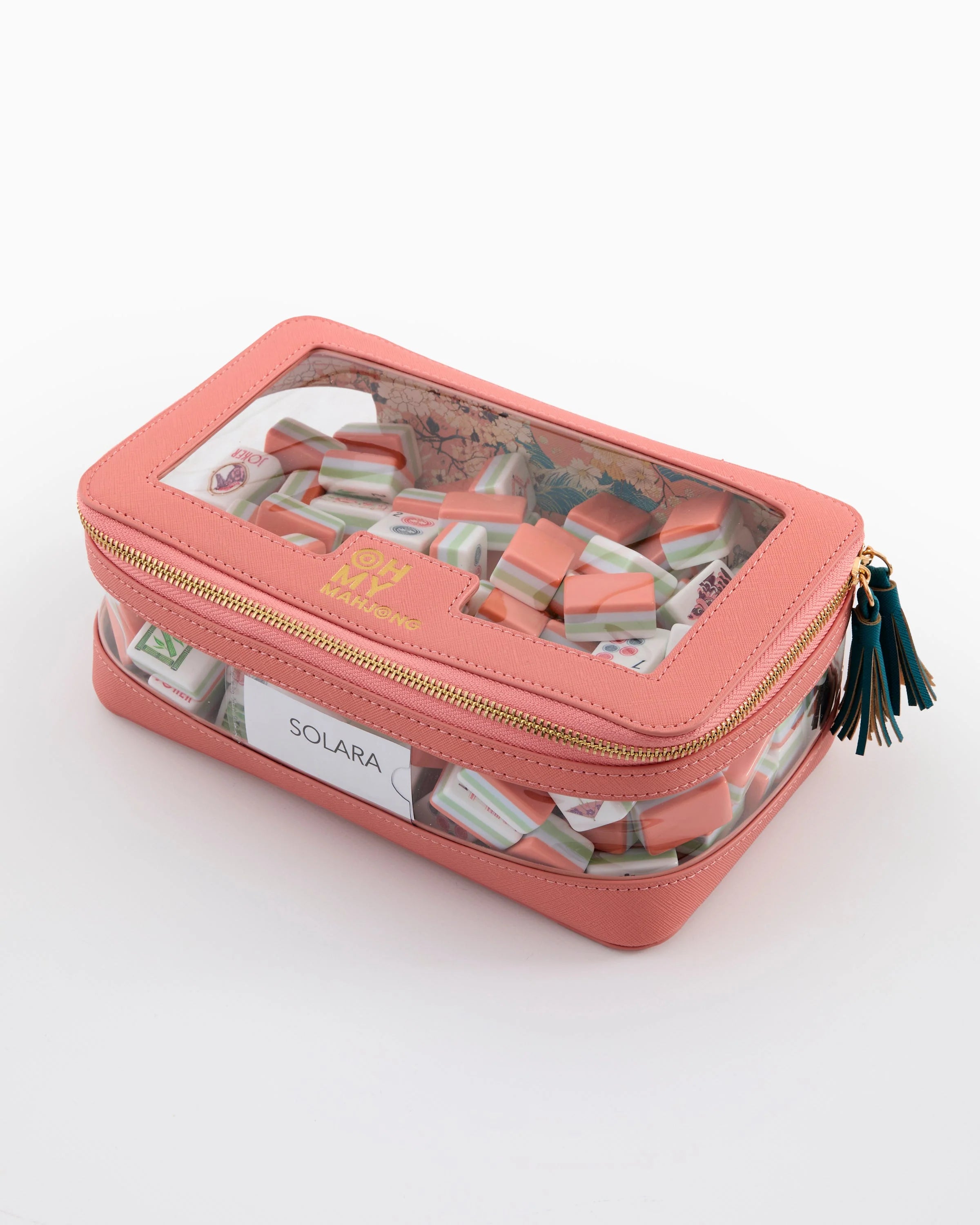 Pink jewelry case with sunglasses and a tassel on a white background