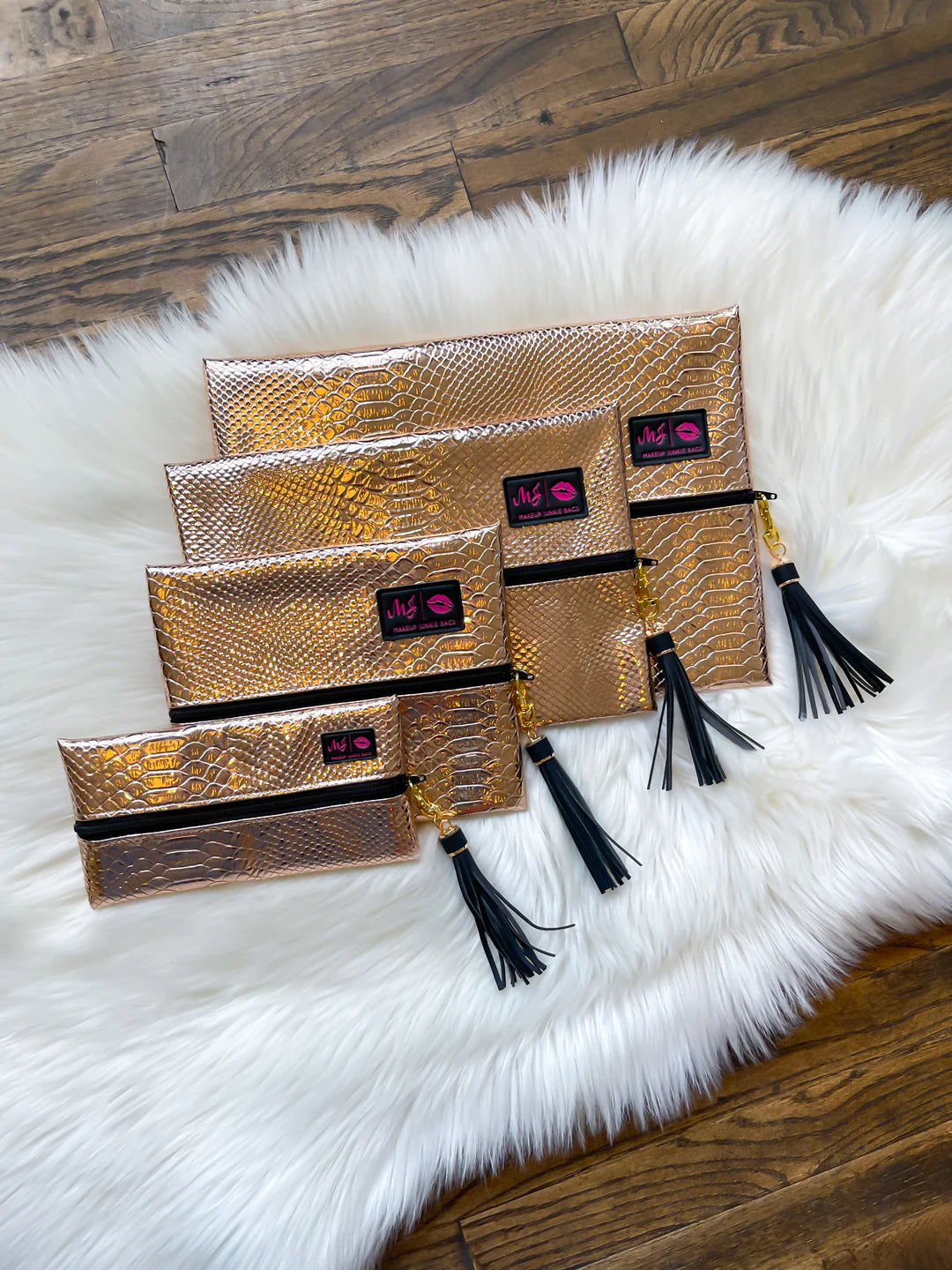 Set of gold clutch bags with black tassels on a white fur surface