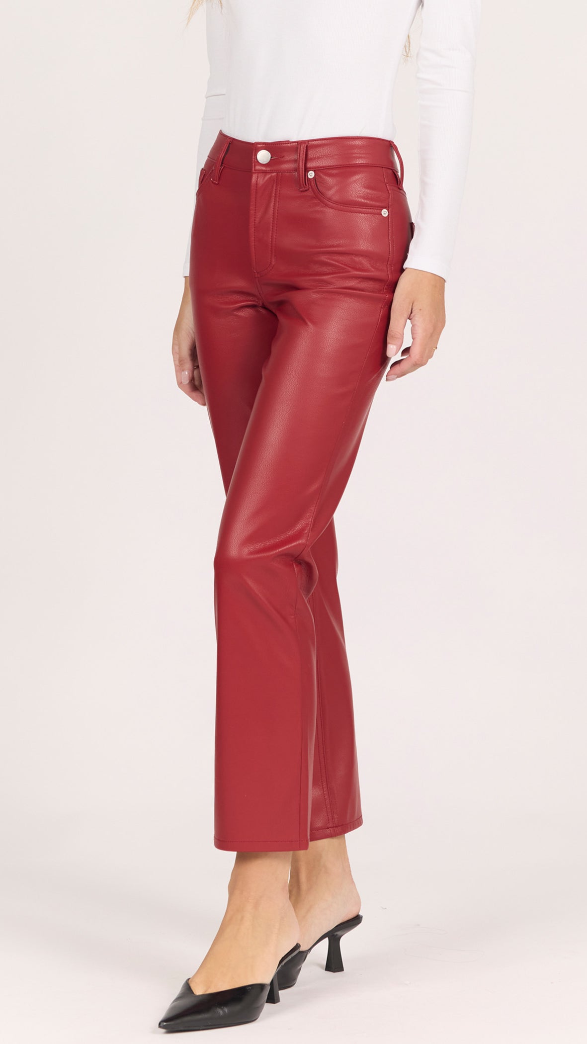Three-quarter side view of crimson red faux leather Anika straight pants with black pointed heels