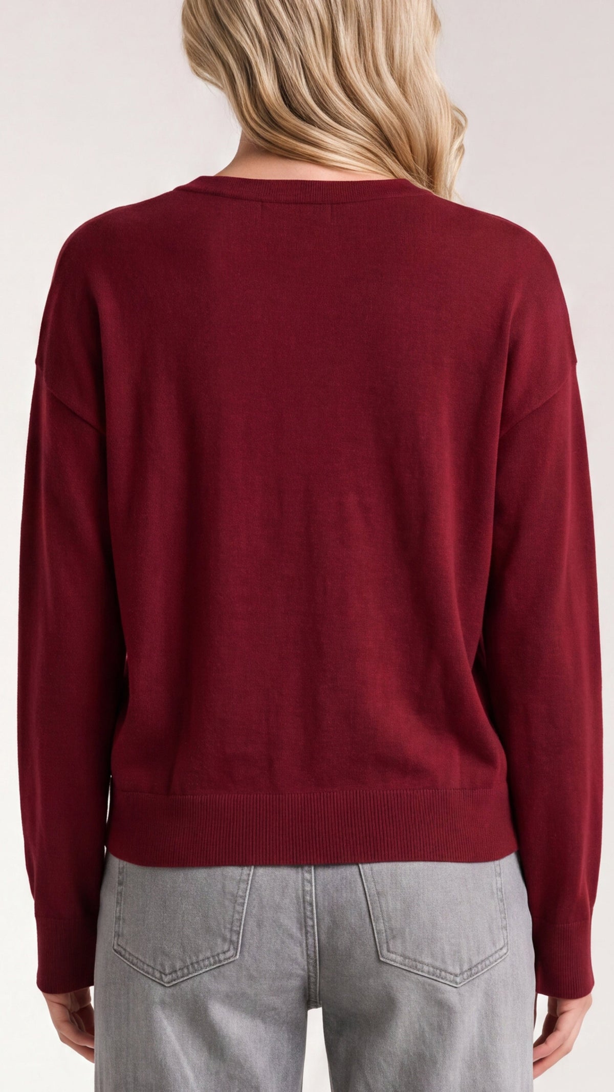 Back view of merlot mixed media sweater with ribbed hem, worn with light gray jeans