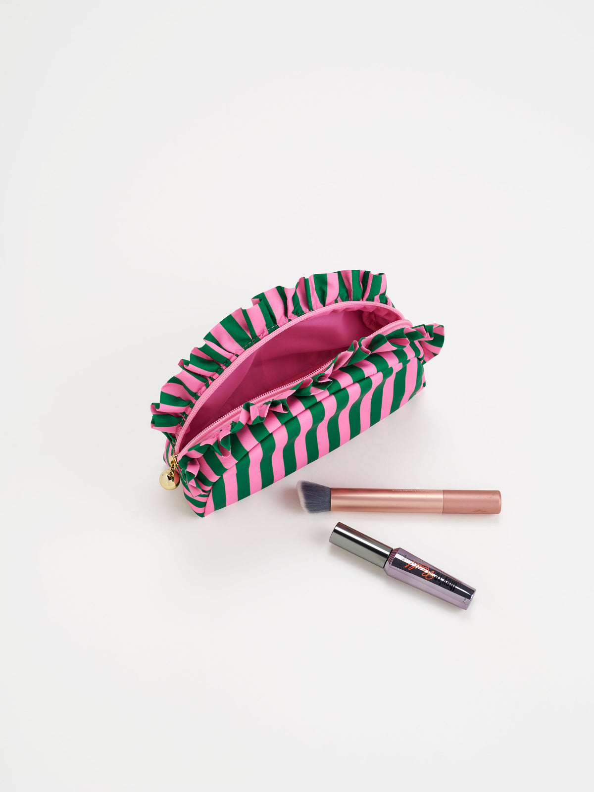 Shiraleah Stripe Ruffle Small Zip Pouch in green and pink stripes, polyester with ruffle trim and gold zipper, open with makeup, detail view