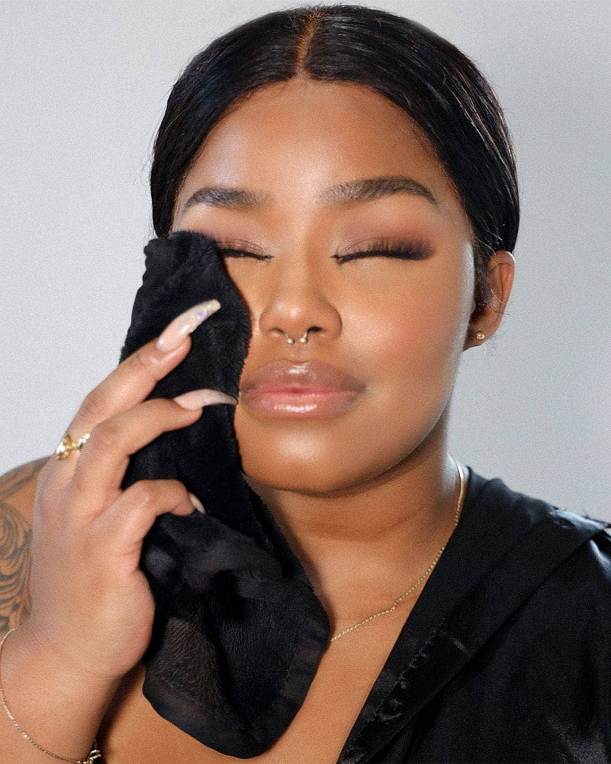 Woman applying makeup with a black cloth on a neutral background