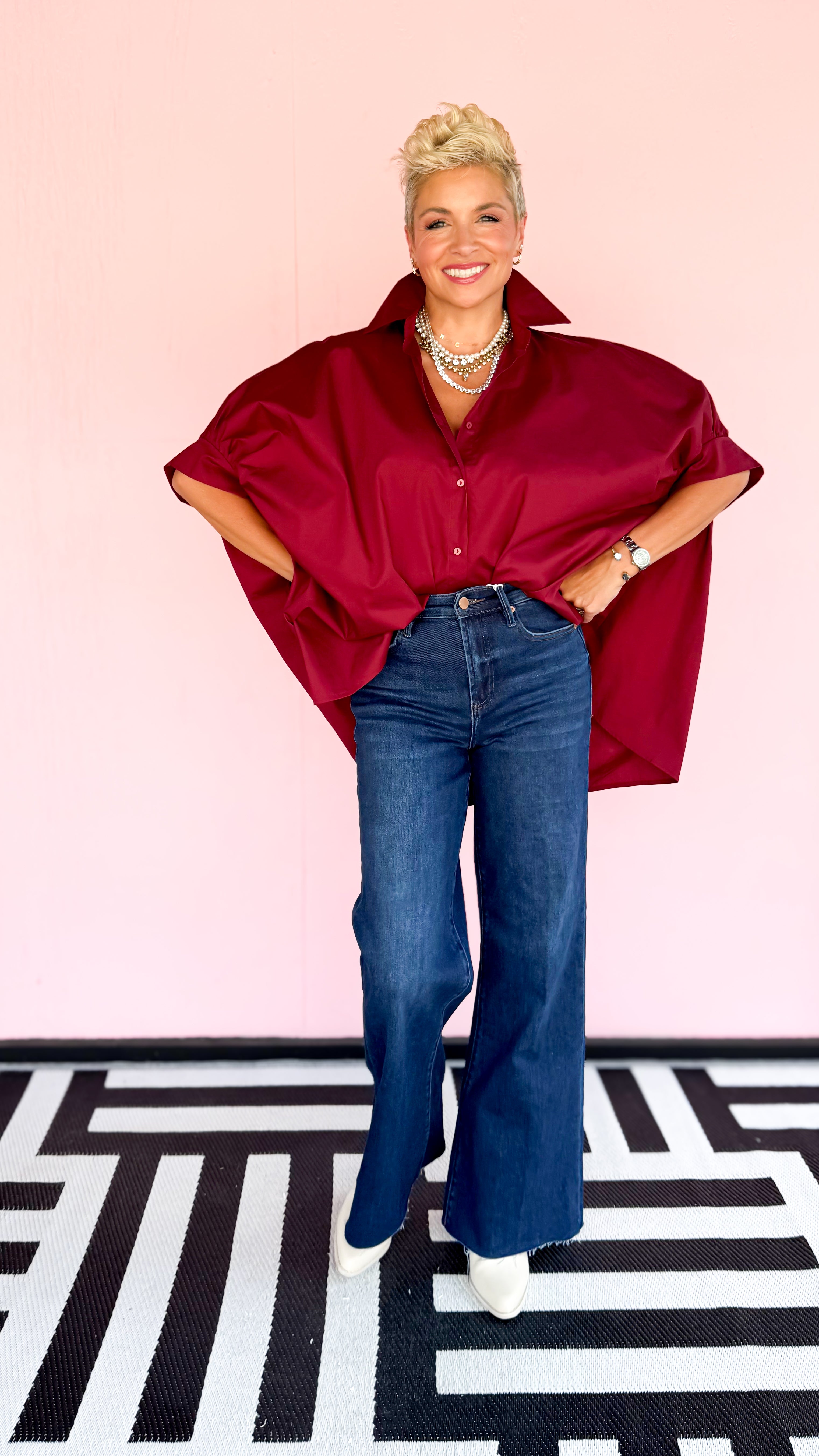 Person wearing a red shirt and blue jeans on a pink background