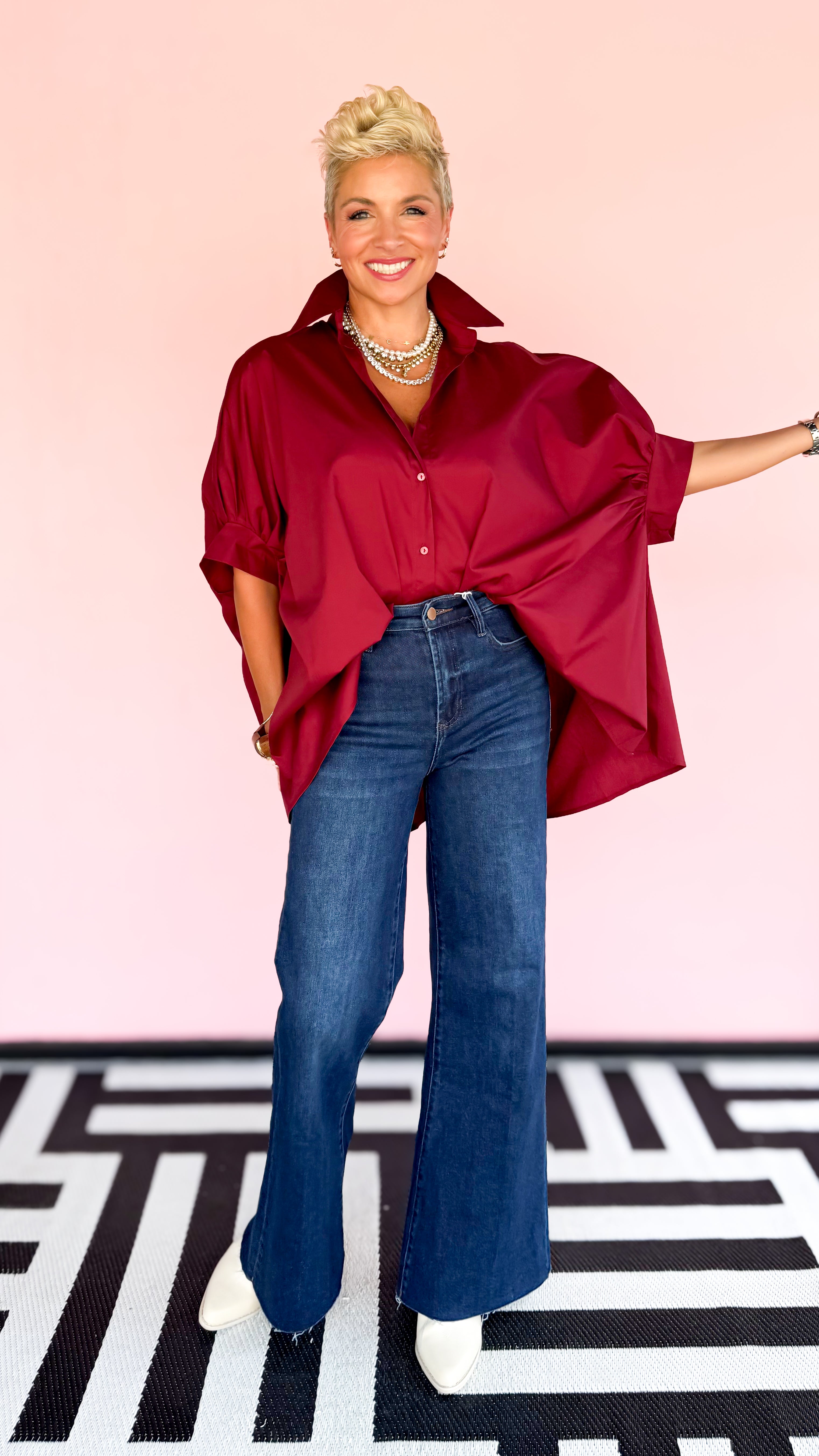 Person wearing a red oversized shirt and blue jeans on a patterned floor.