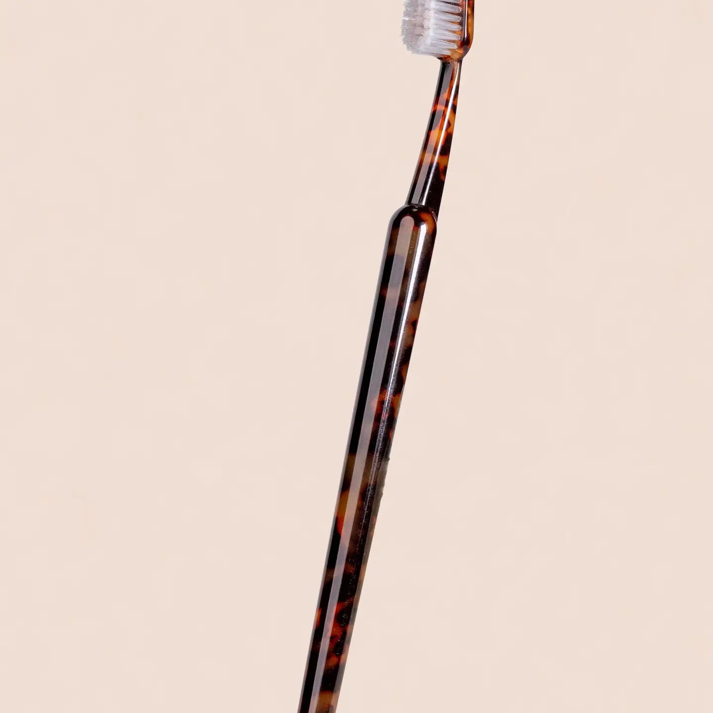 Tortoiseshell-patterned toothbrush on a beige background