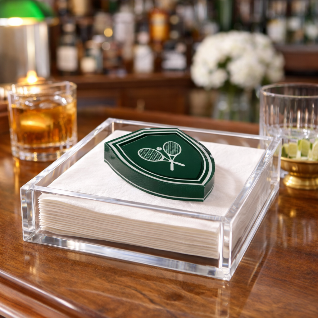 Napkin holder with a green logo on a bar counter with drinks and decor.