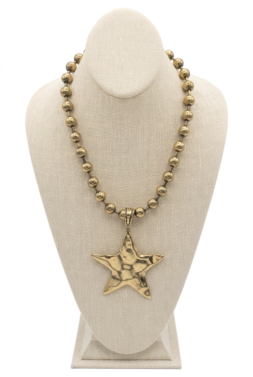 Accessories to Go XL Star Necklace with gold-tone beads and an oversized hammered star pendant on a linen bust