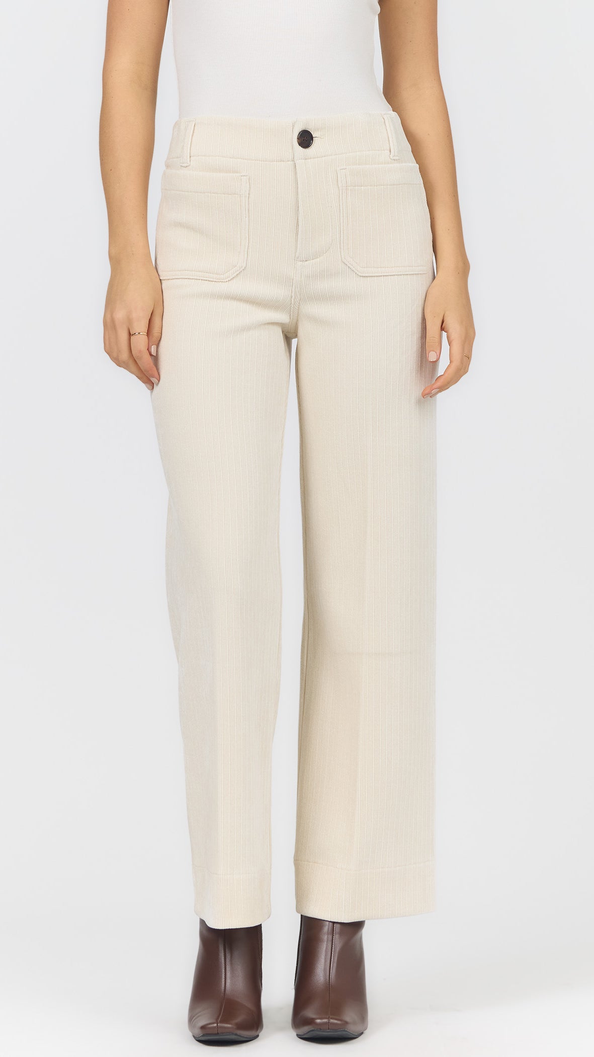 Front view of egret corduroy wide leg pants showing the front patch pockets, single button, and brown heeled ankle boots