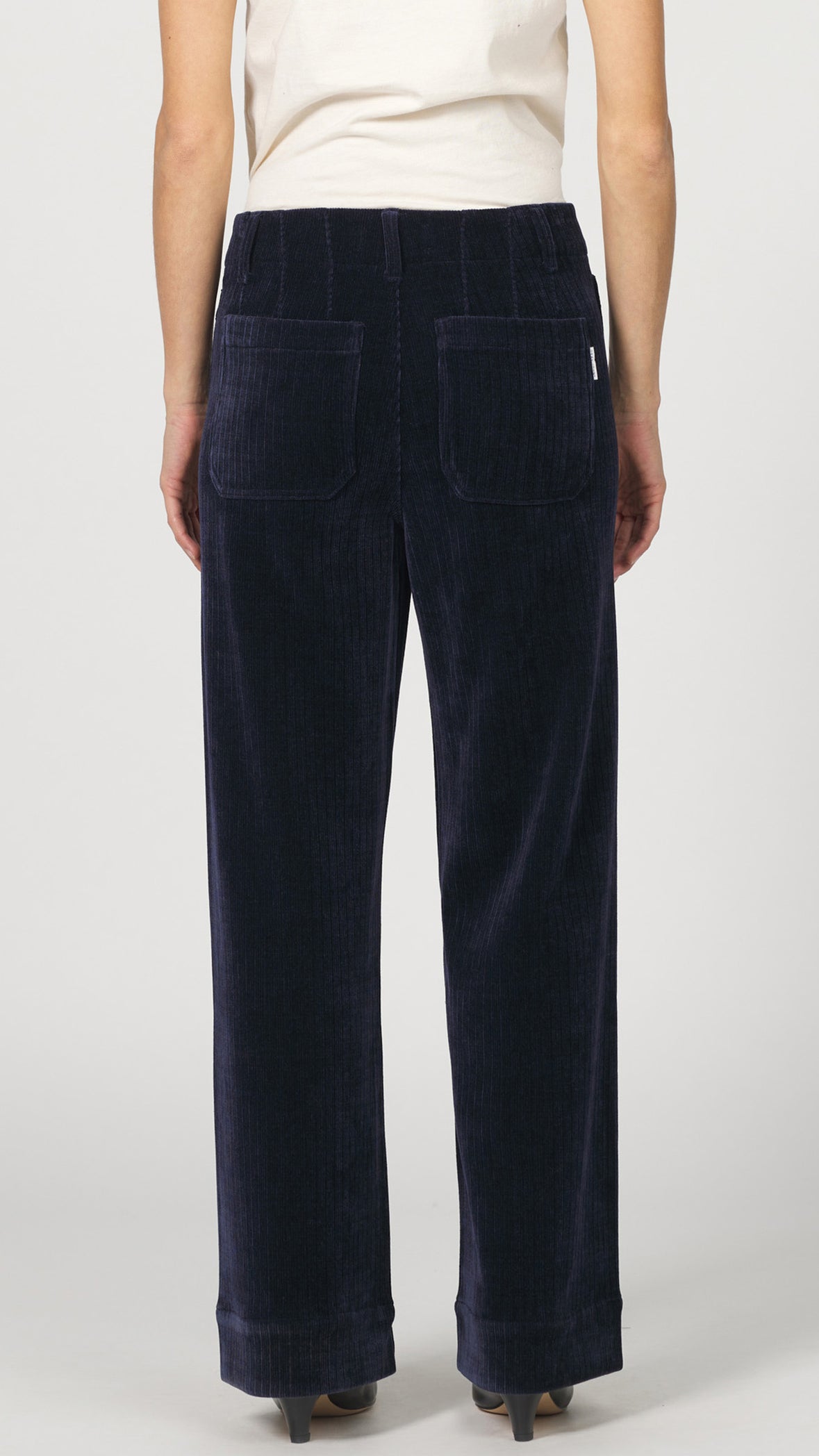 Back view of black iris corduroy wide leg pants showing the back patch pockets and leather label